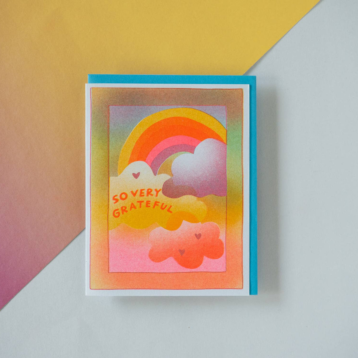 Colorful greeting card with rainbow and cloud design on a gradient background