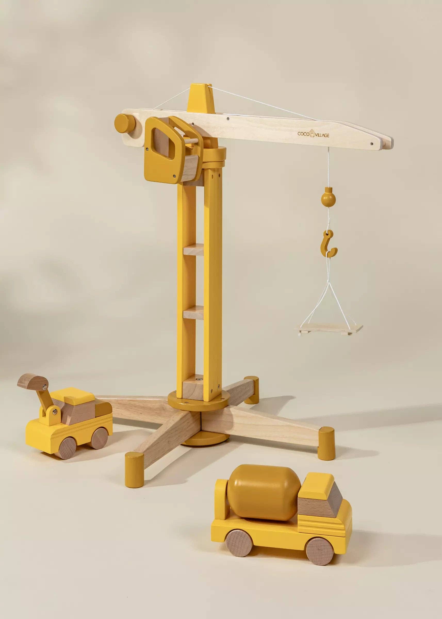 Wooden toy crane and trucks on a neutral background