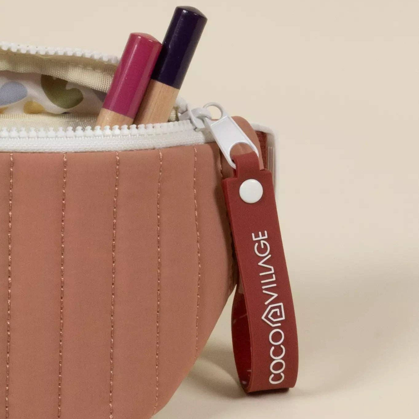 Cosmetic bag with lipsticks and a visible brand tag on a beige background