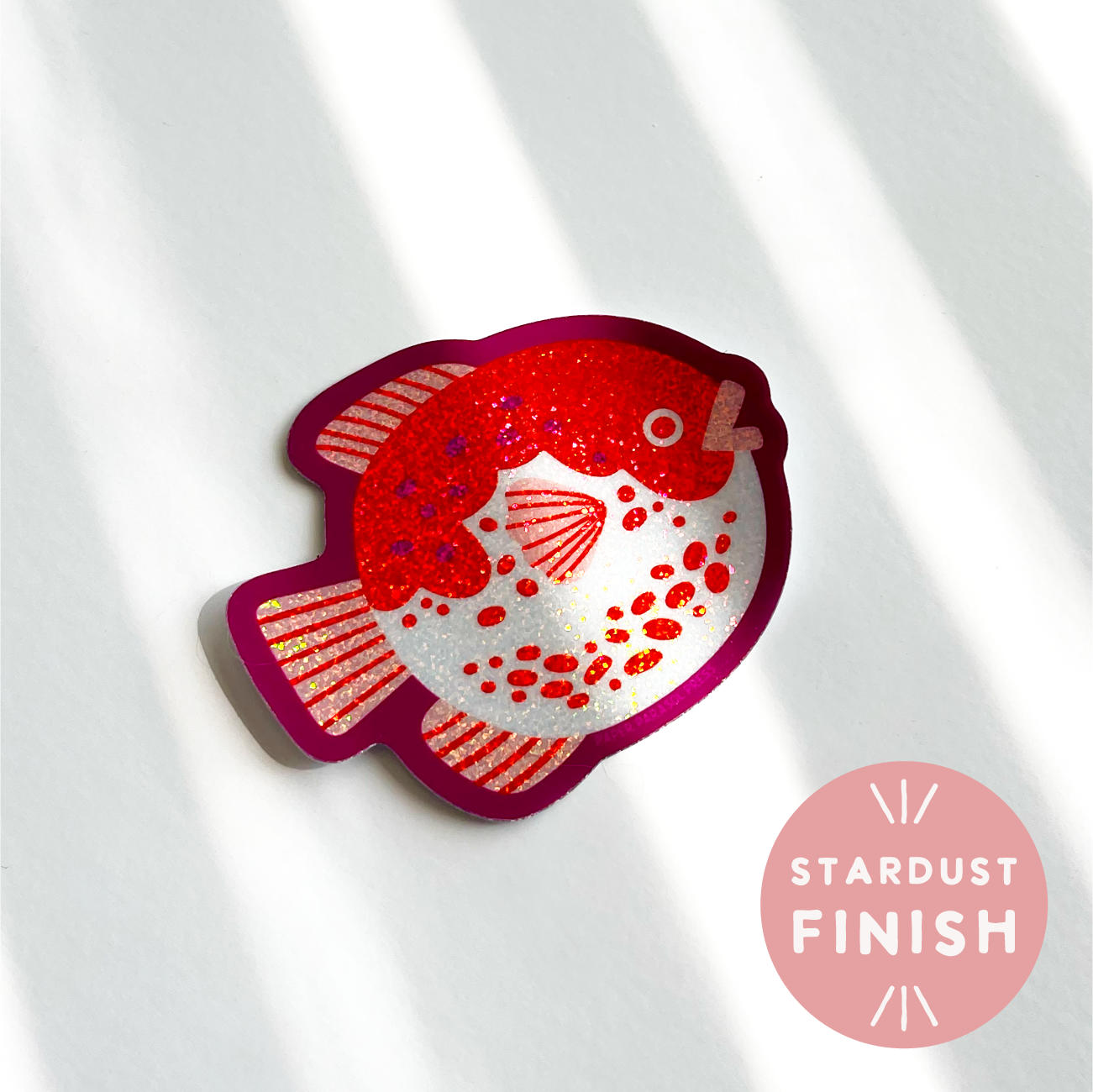Red fish-shaped object with a stardust finish on a white background
