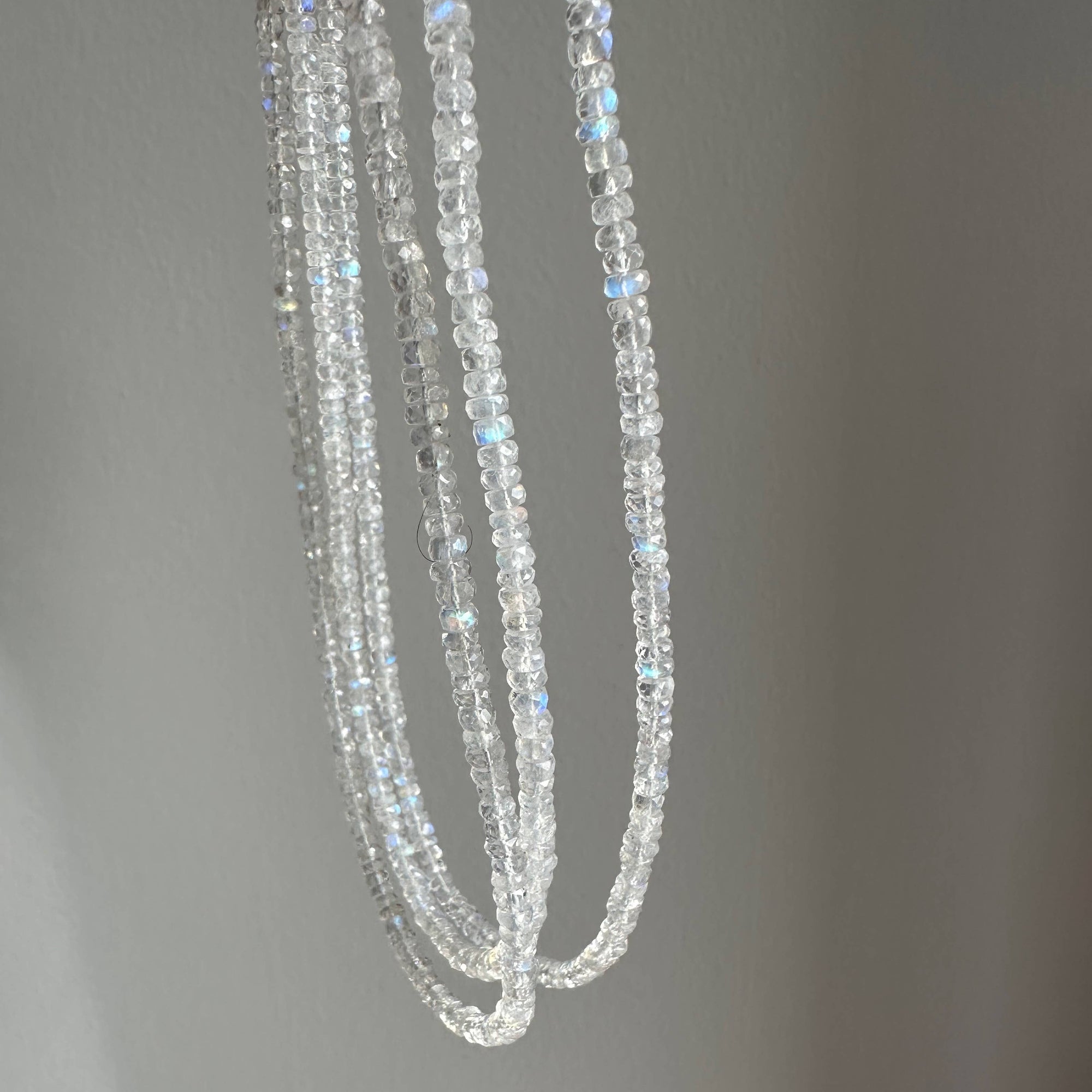 Three strands of clear beads on a gray background