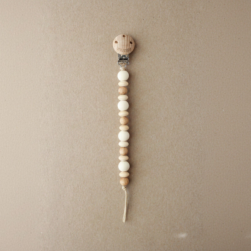 Wooden pacifier clip with beads on a beige background