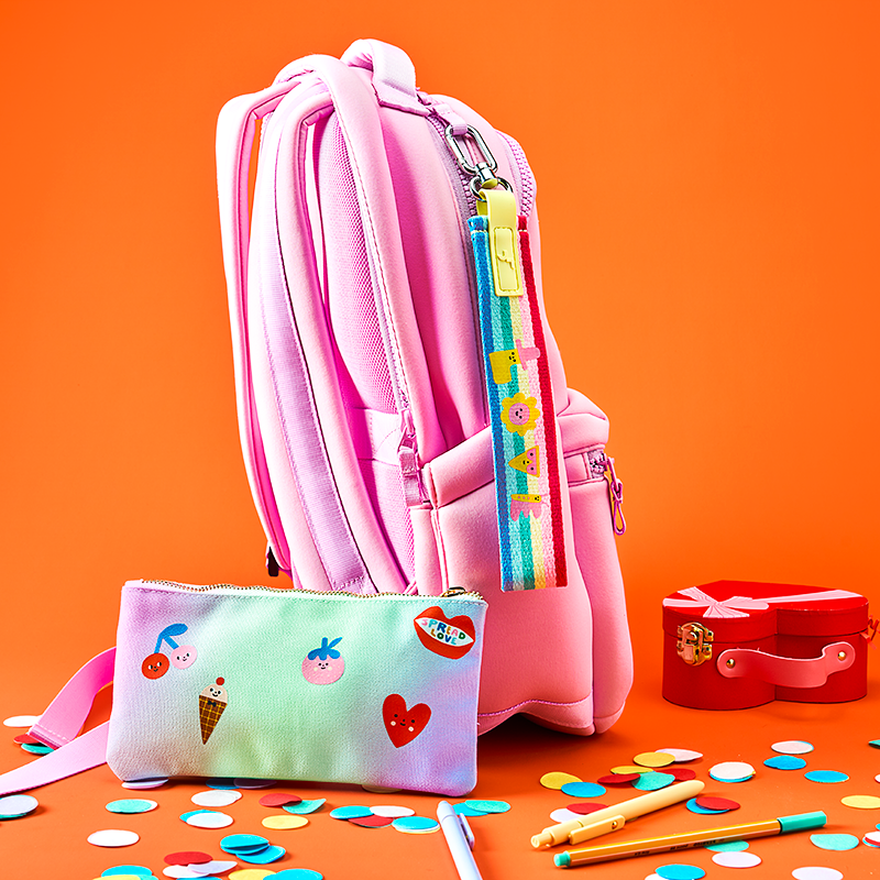 Pink backpack with colorful accessories on an orange background