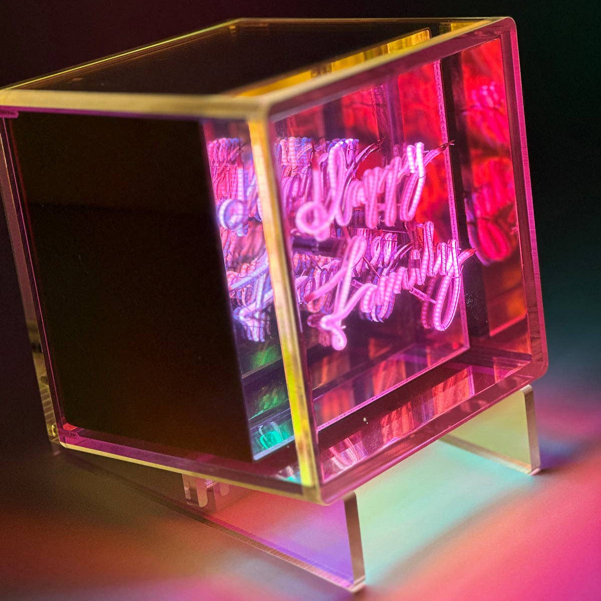 Neon sign with 'Happy Birthday' text on a stand against a dark background