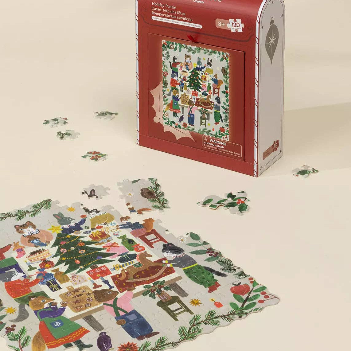 Christmas-themed puzzle with pieces scattered on a beige surface and a red and white box in the background.