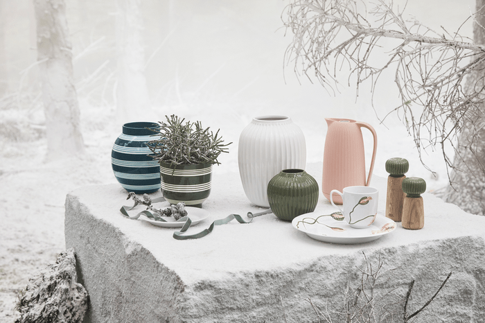 Decorative table setting with vases, a teapot, and a mug on a snowy background