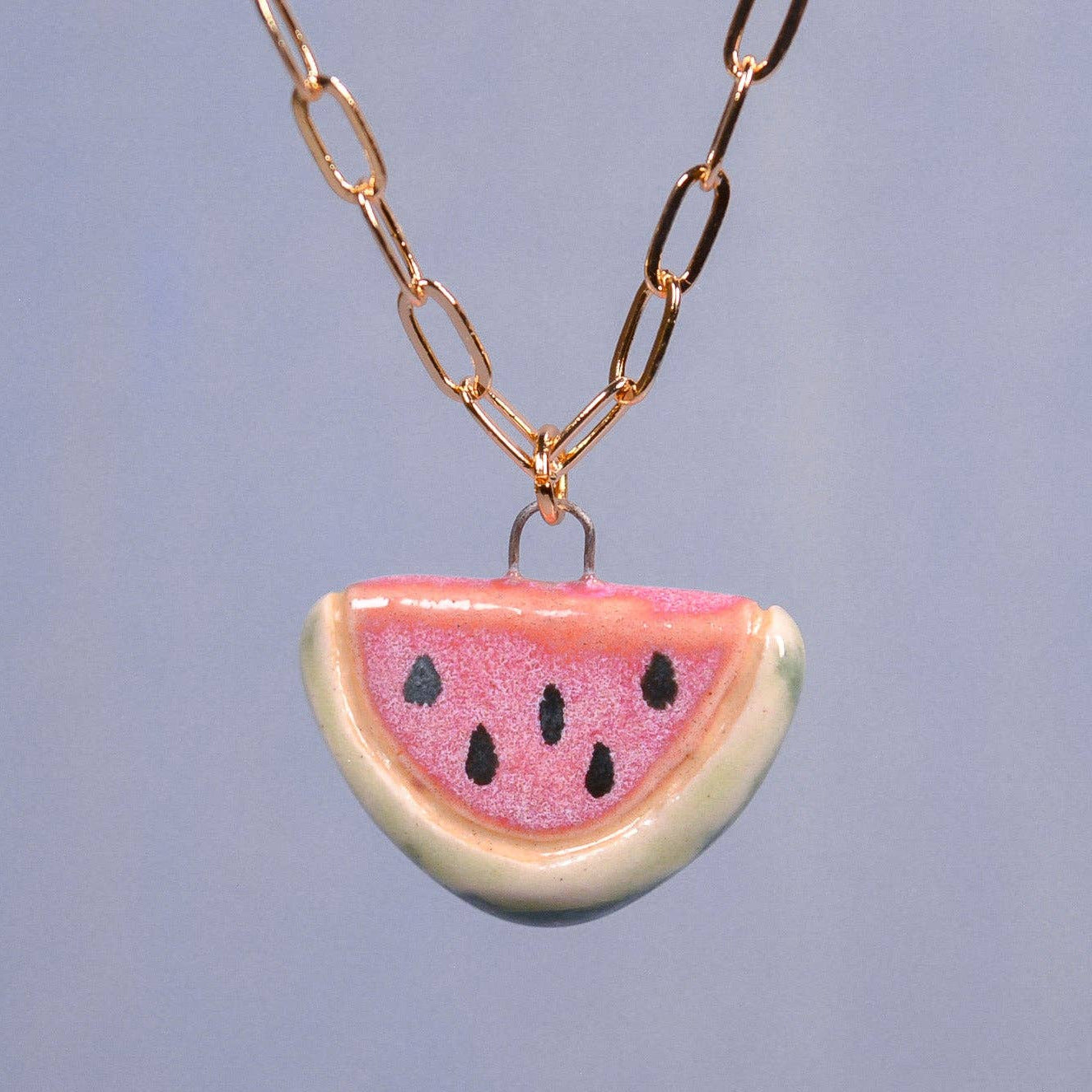 Necklace with a watermelon slice pendant on a plain background
