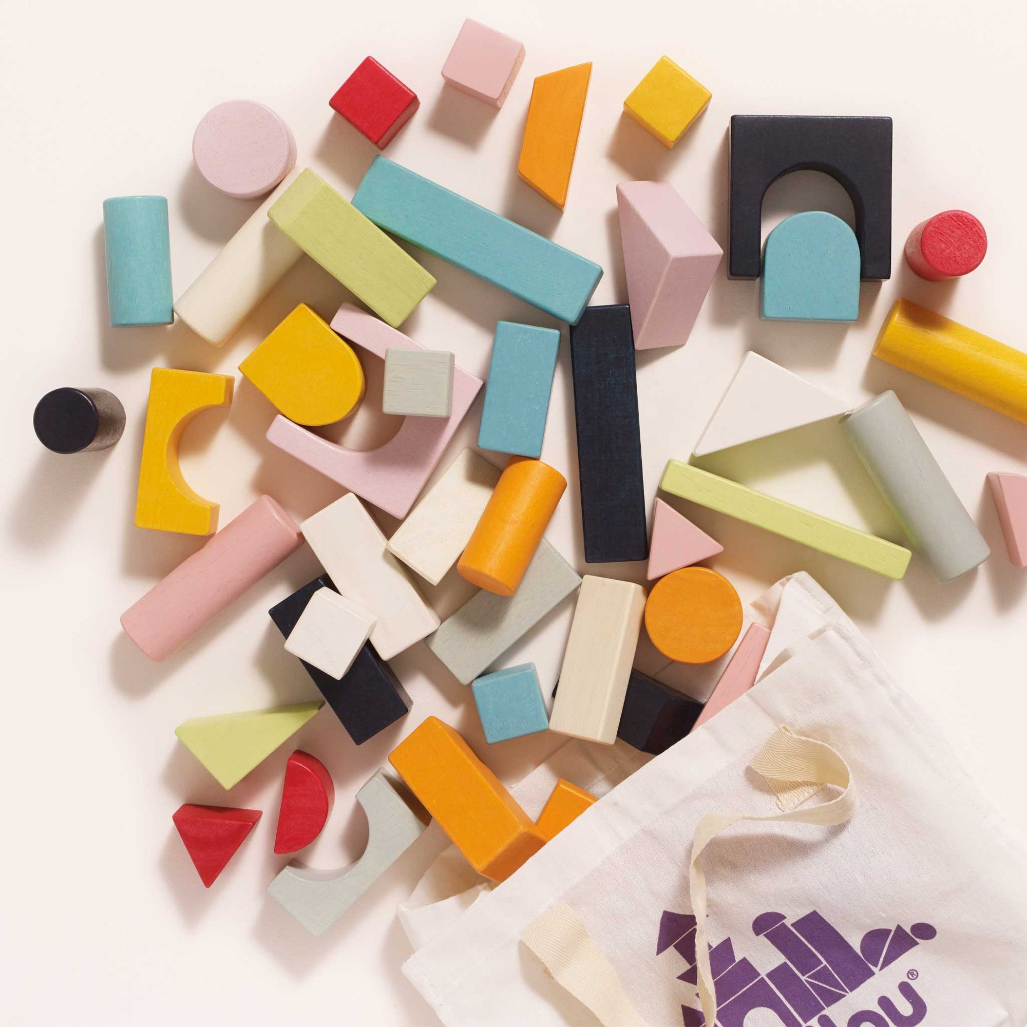 Colorful wooden blocks scattered on a white surface with a branded bag.