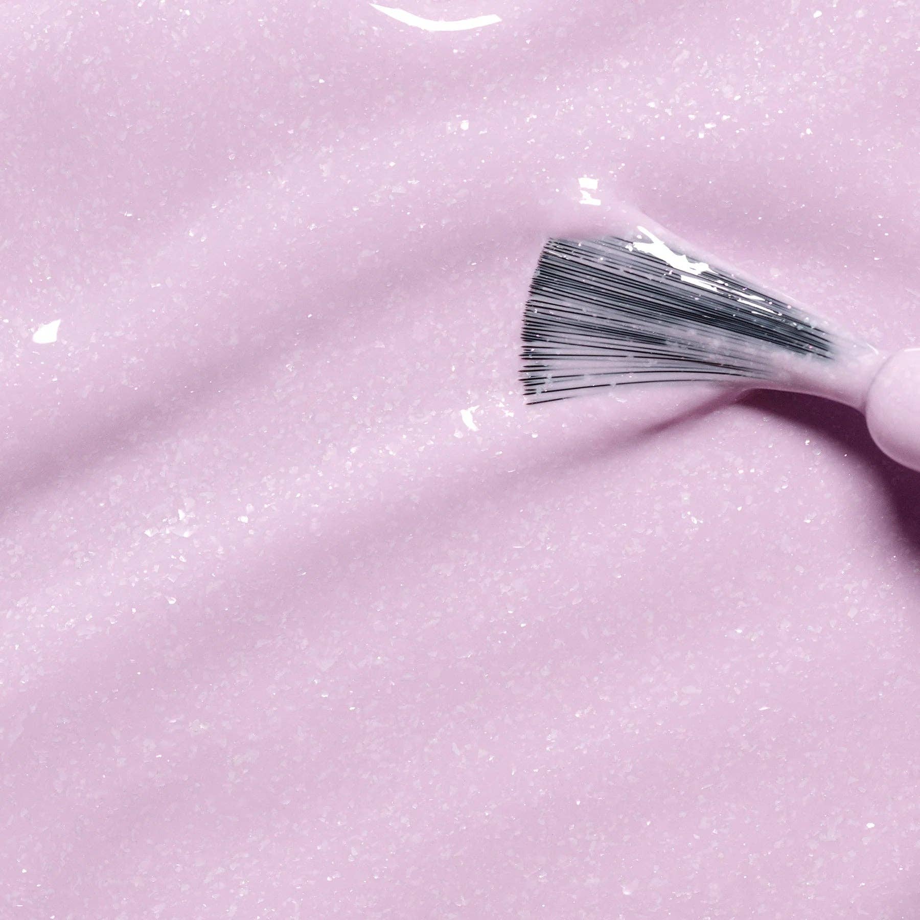 Close-up of a brush浸入粉色闪亮的液体中