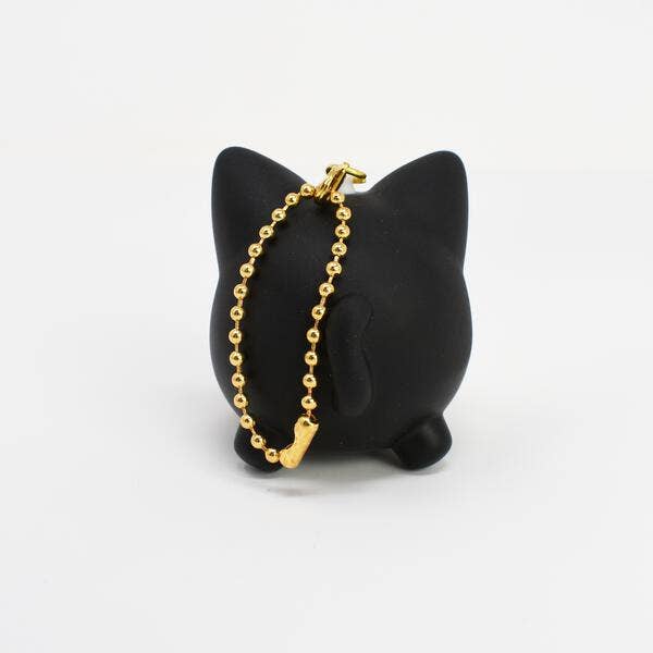 Gold bracelet on a black cat-shaped stand against a white background