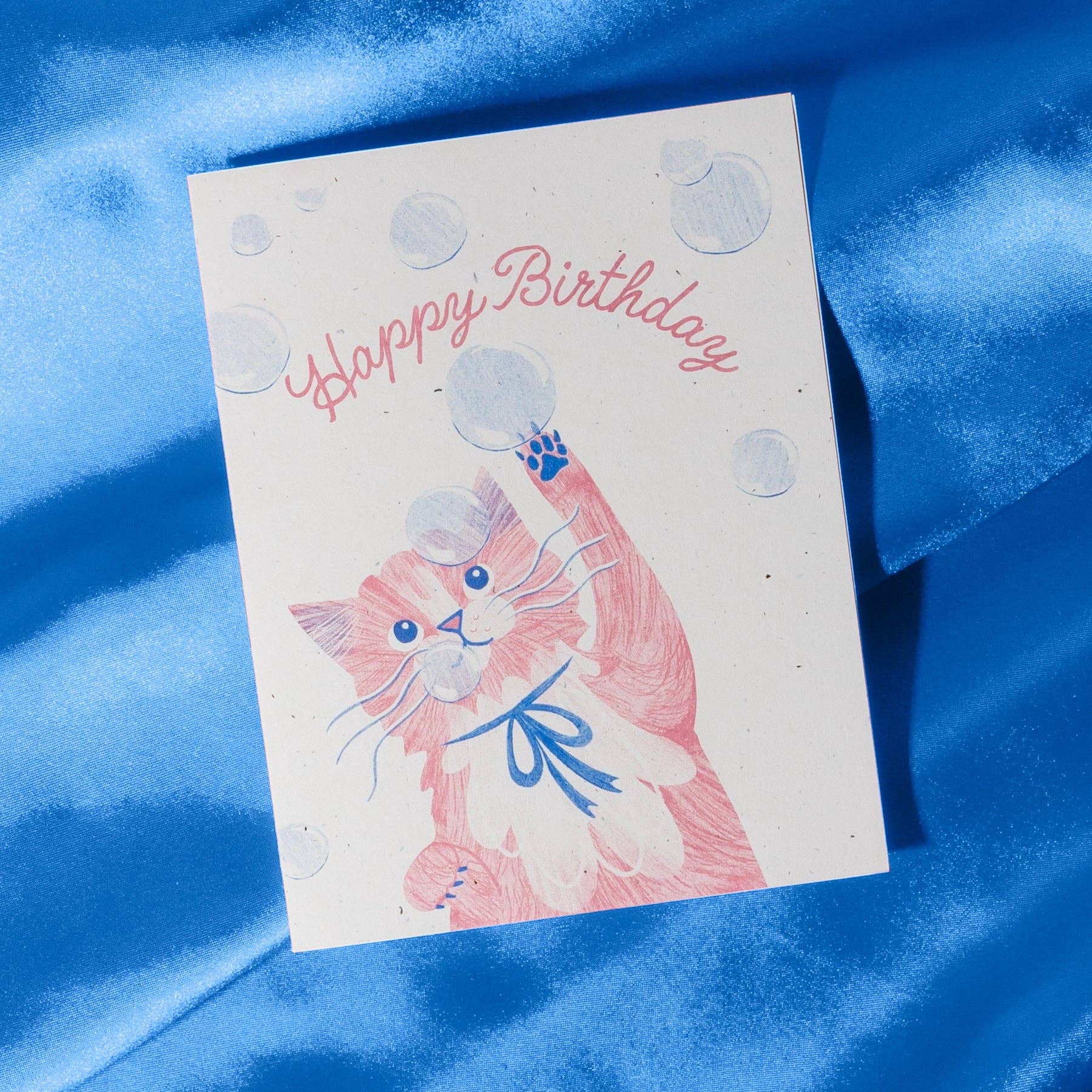 Birthday card with a cat illustration on a blue fabric background