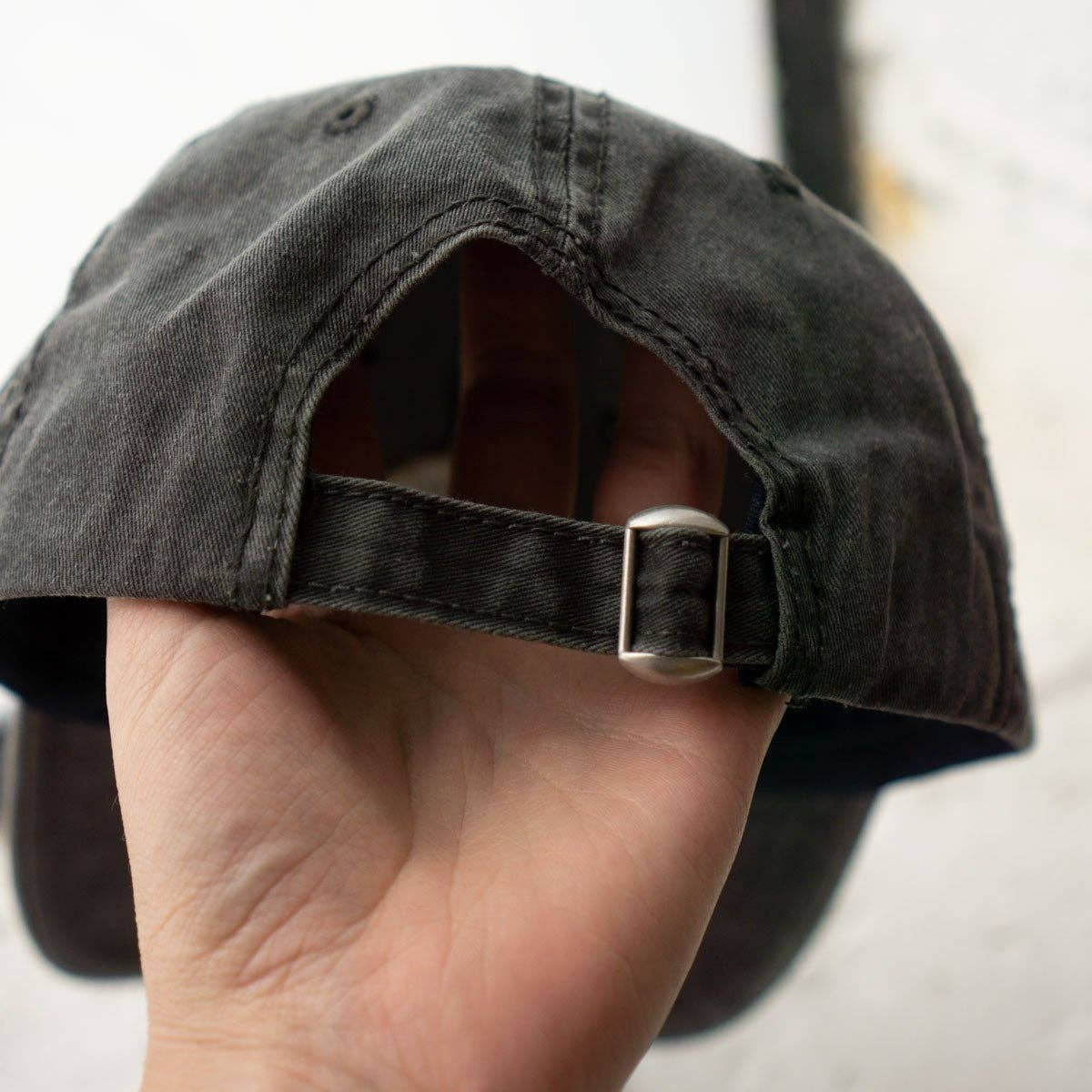 Black cap held by a hand against a white background