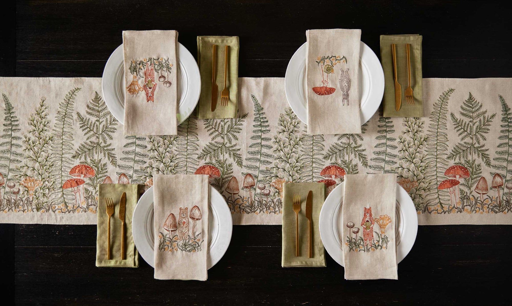 Table setting with white plates, patterned napkins, and a decorative runner on a dark surface.