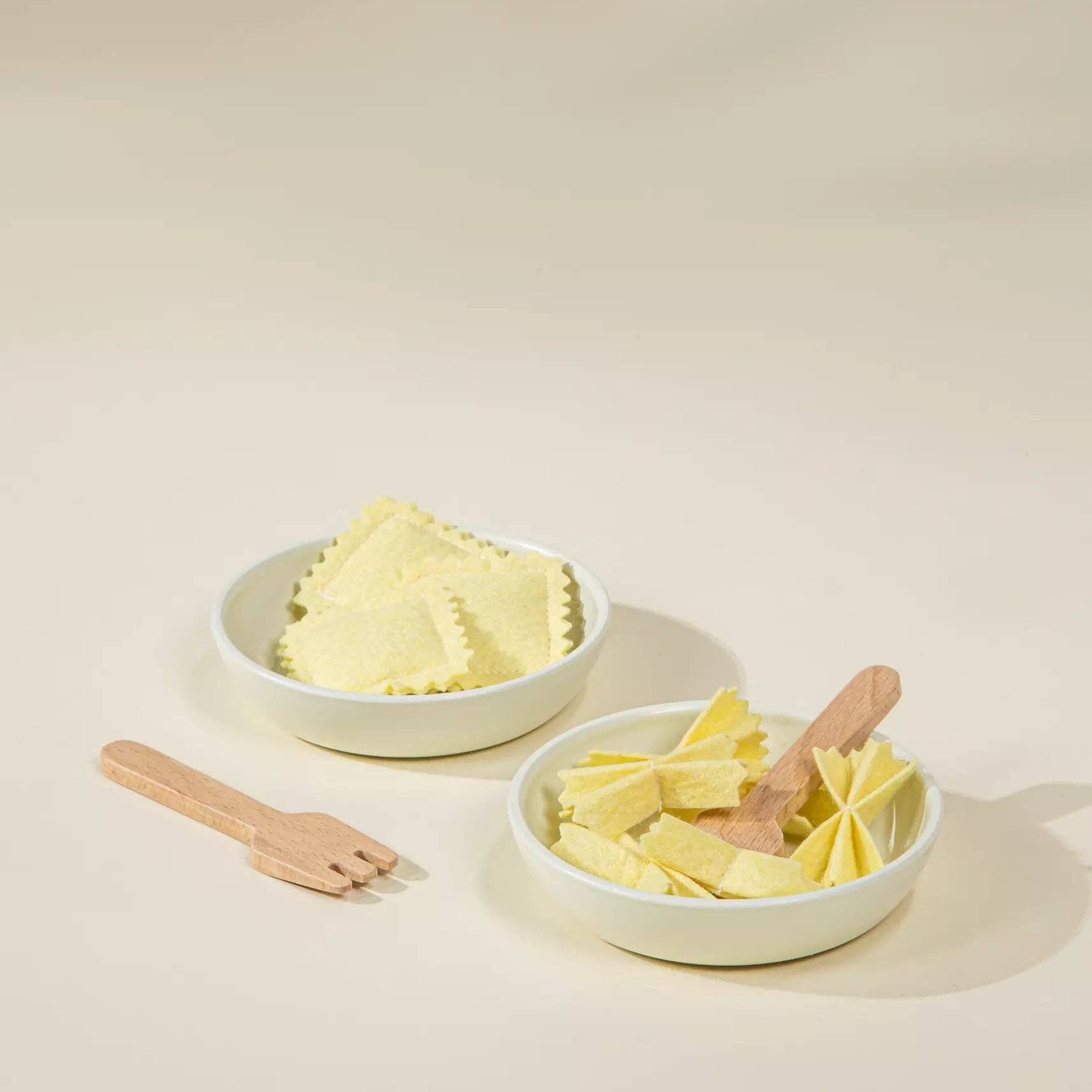 Two white bowls filled with ravioli on a beige background