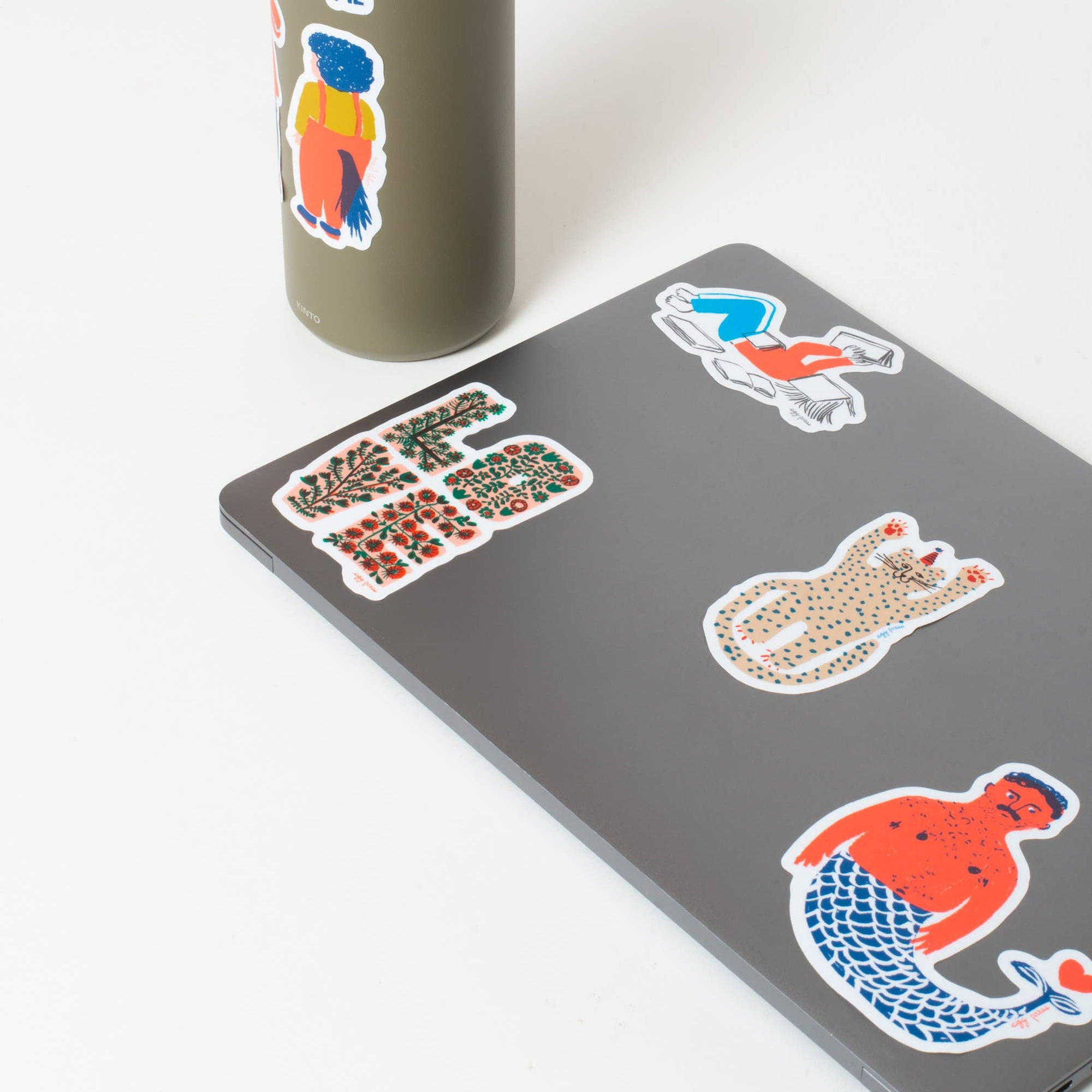 Gray tumbler with colorful stickers on a white background