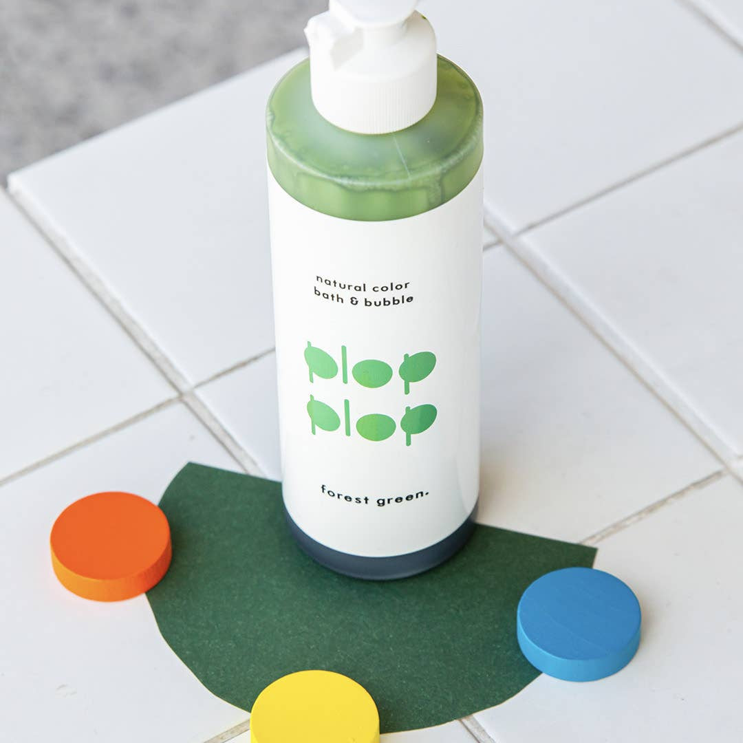 Bottle of 'Forest Green' bath & bubble product on a tiled floor