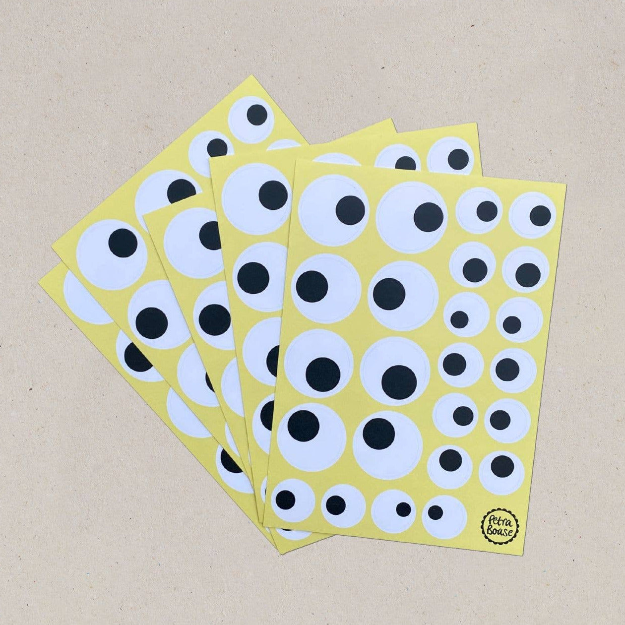 Three sheets of round stickers with black and white circles on a beige background