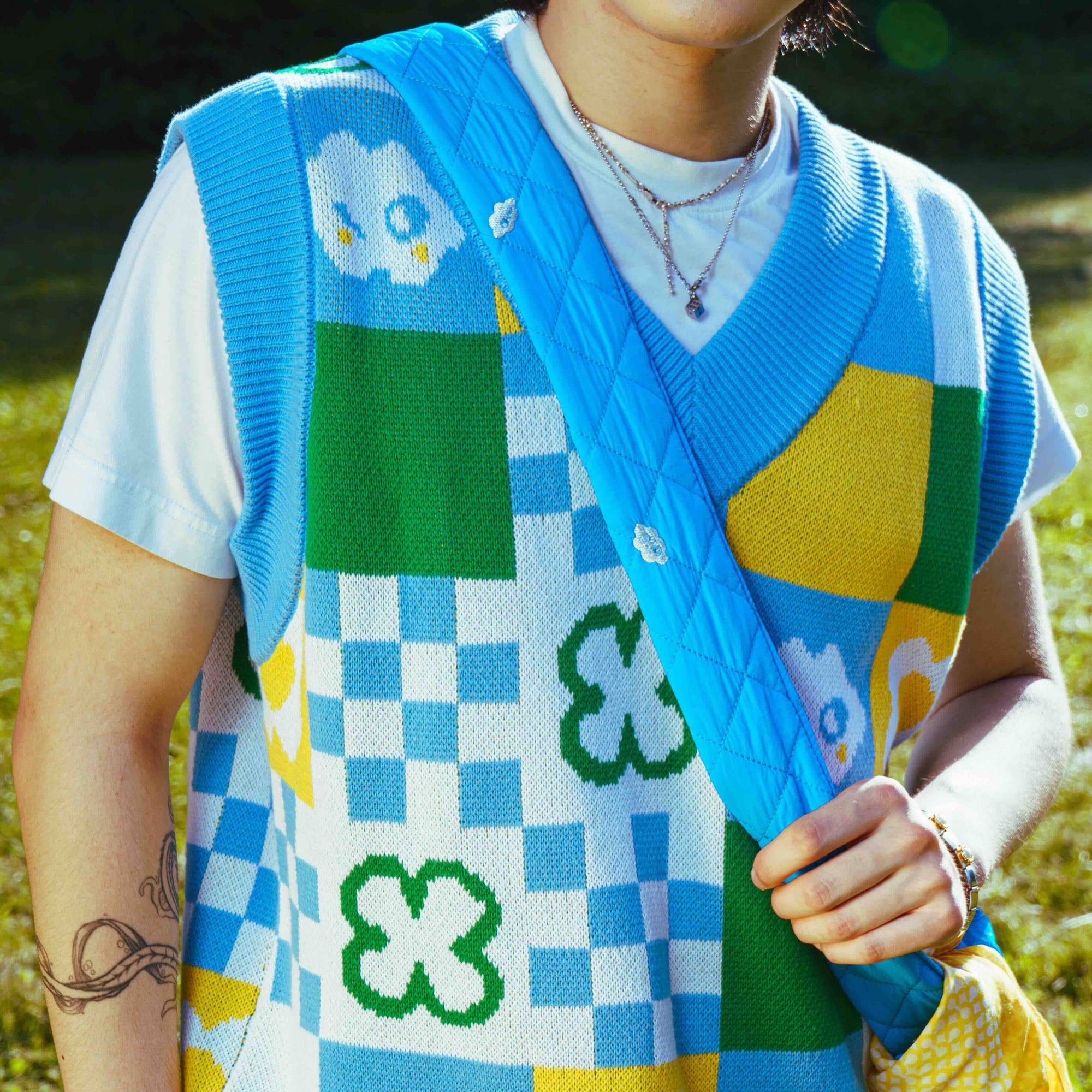 Person wearing a colorful patchwork vest with a pattern of flowers and geometric shapes.