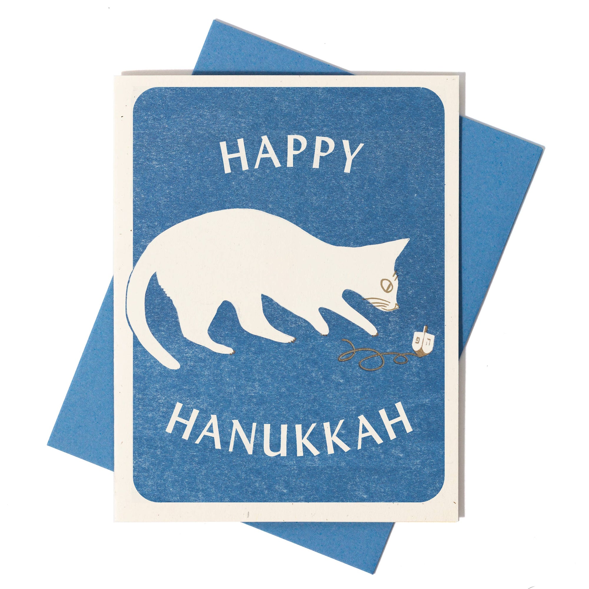 Greeting card with a cat and dreidel design, text 'Happy Hanukkah' on a blue background.