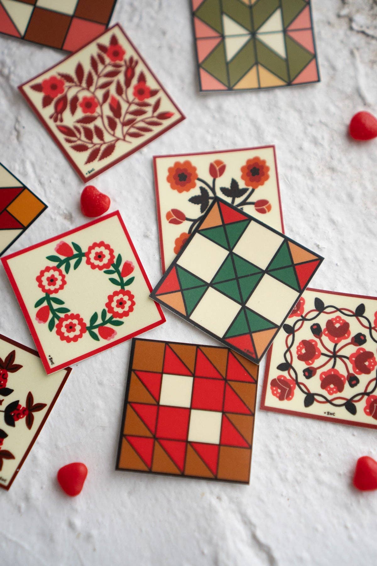 Colorful quilt-style cards with floral and geometric patterns on a textured surface.