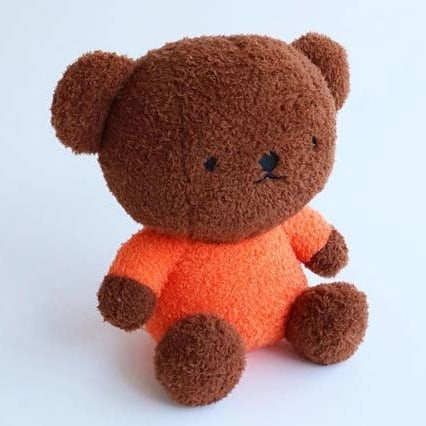 Plush toy bear with an orange shirt on a white background