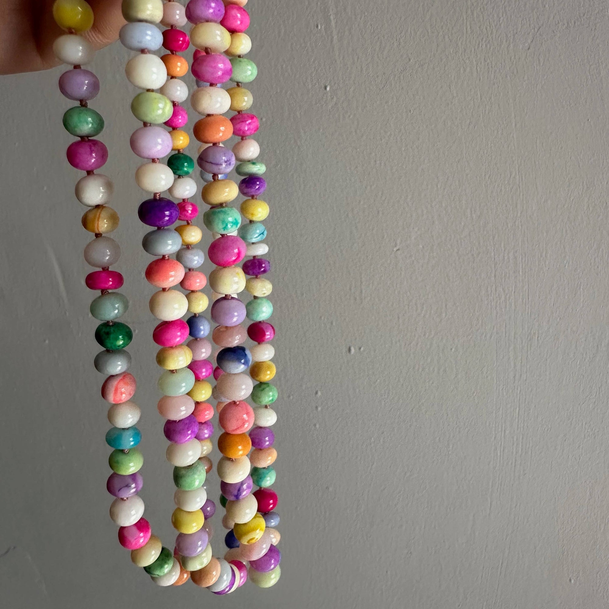 Colorful beaded necklace held against a plain background