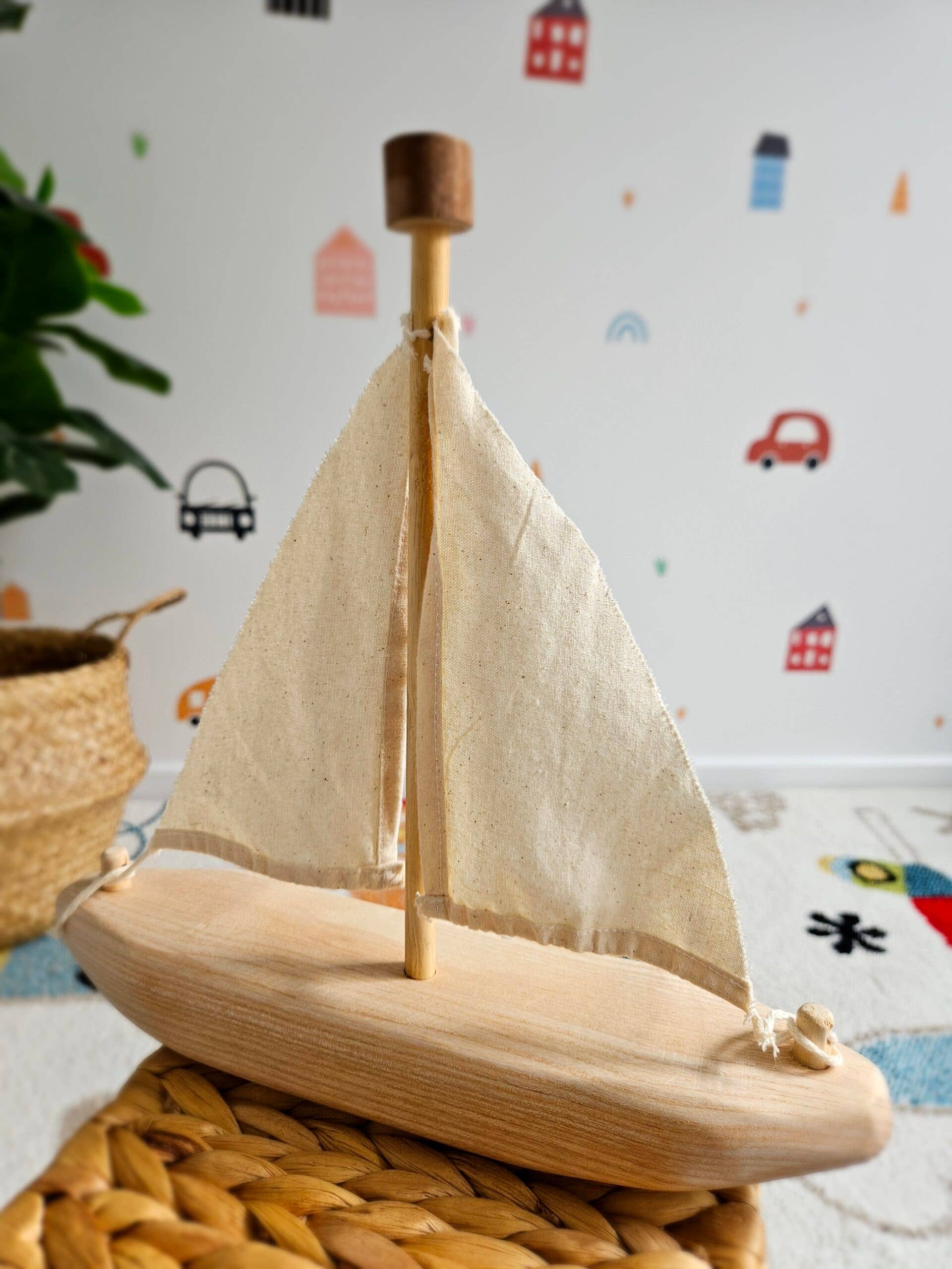 Wooden sailboat model on a textured surface with a colorful wall in the background