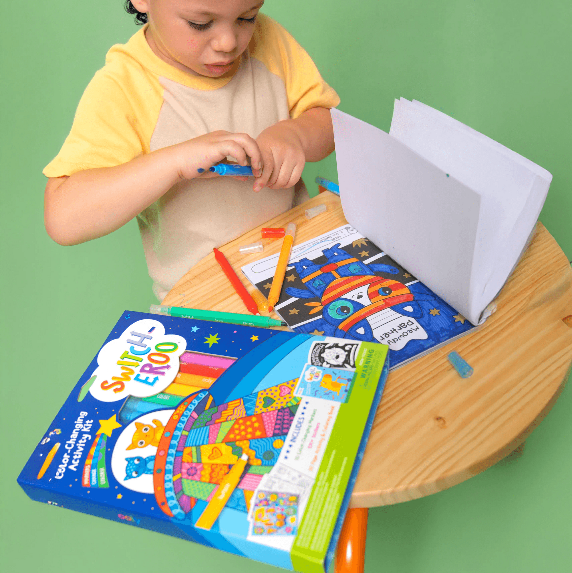 Child playing with a toy train set on a small table against a green background