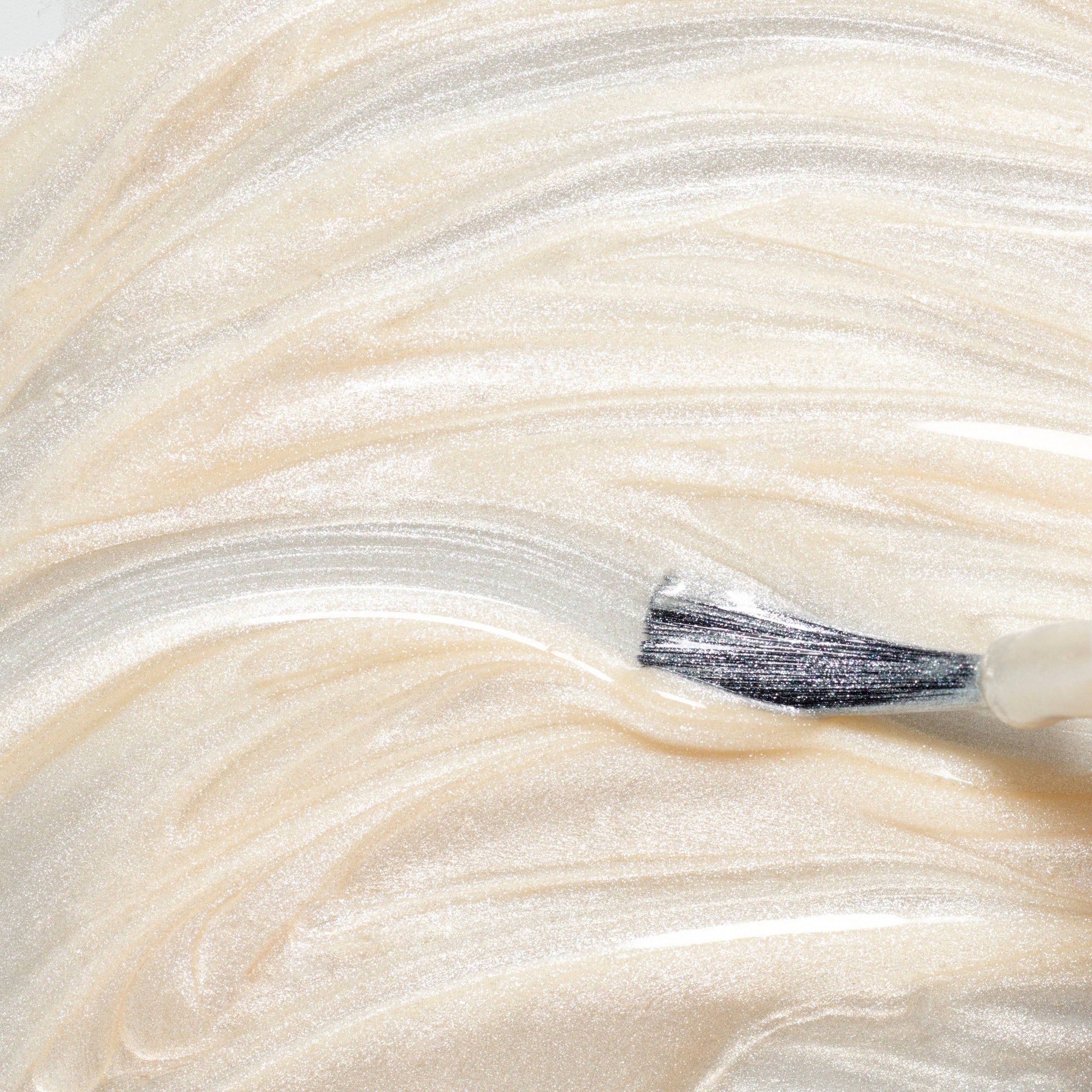 Close-up of a brush applying cream on a beige background