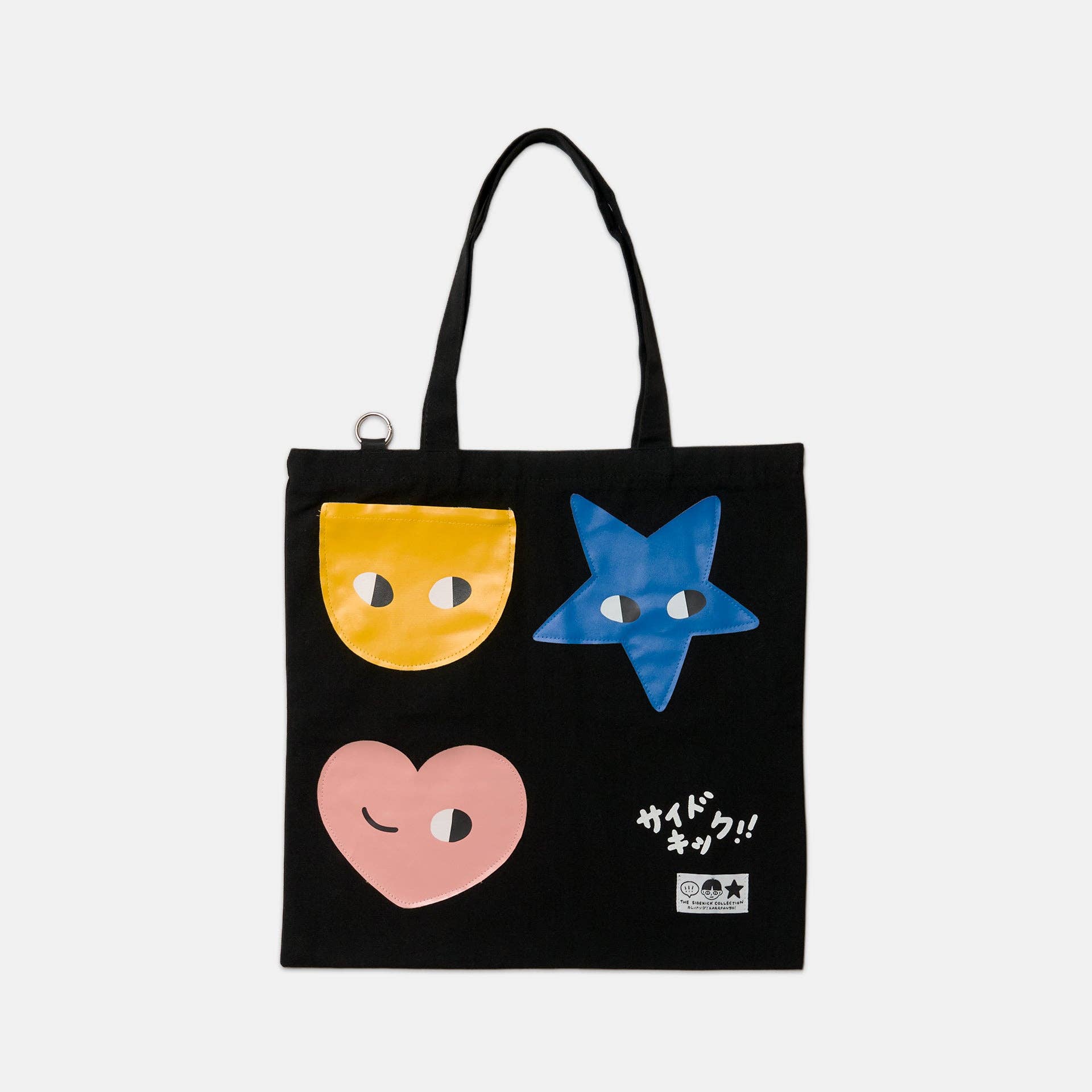 Black tote bag with colorful face designs on a white background