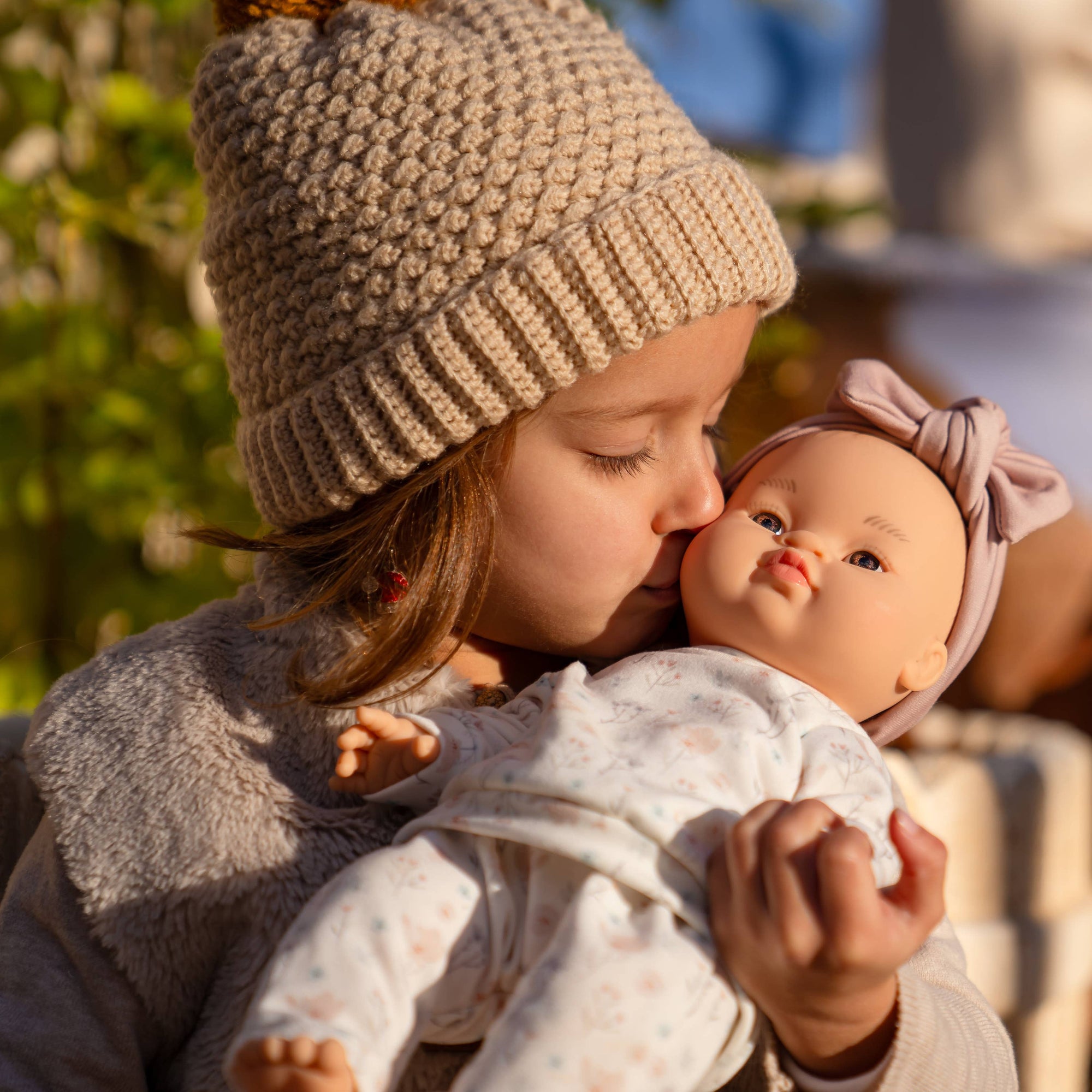 Child holding a doll close together outdoors