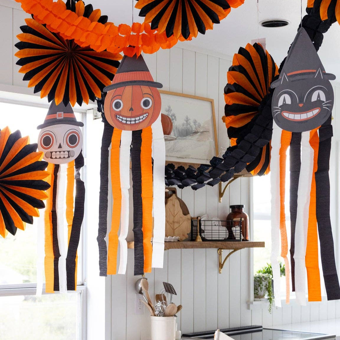 Halloween-themed dining room with black and orange decorations, including jack-o'-lantern faces on streamers.