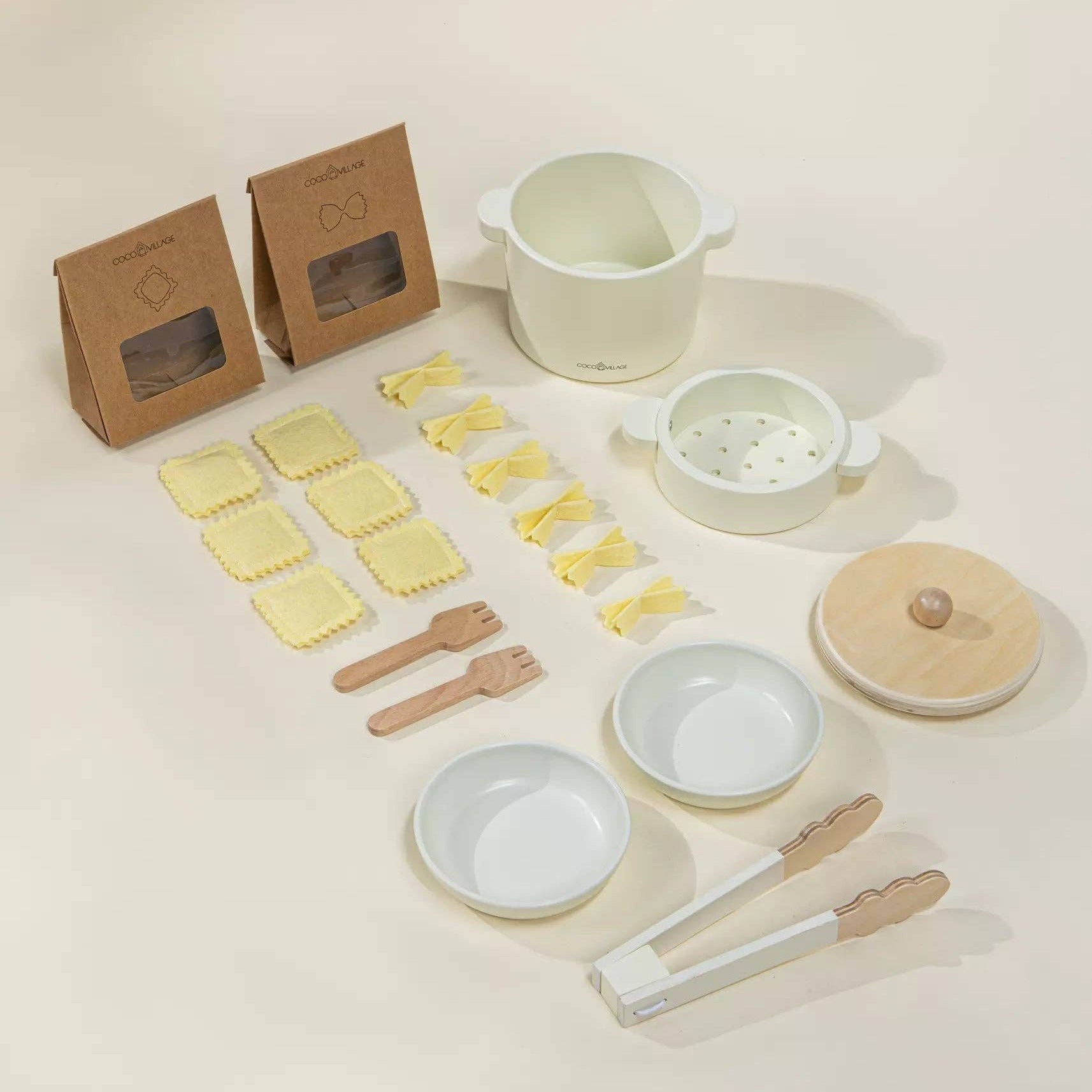 Set of ceramic kitchenware items including bowls, a pot, and utensils on a light background