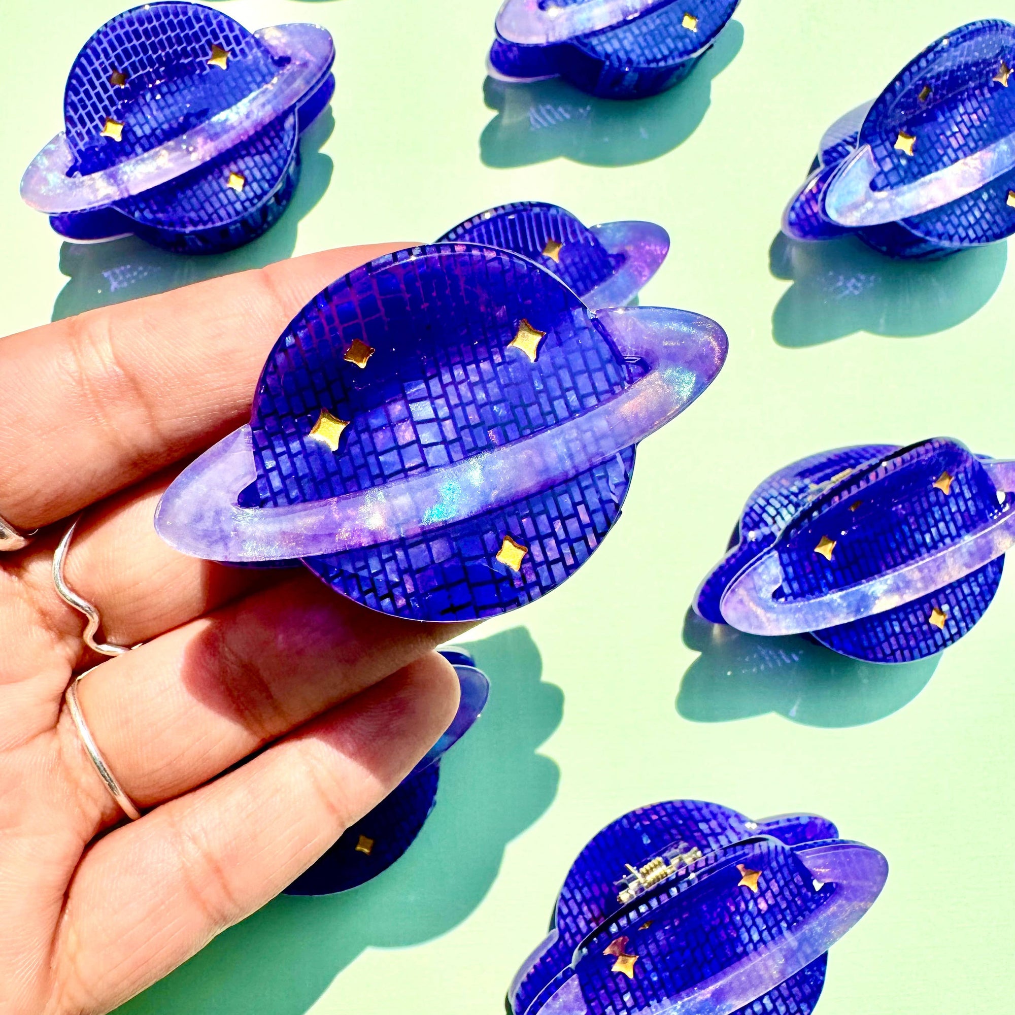 Hand holding a blue disco ball with stars on a light green background