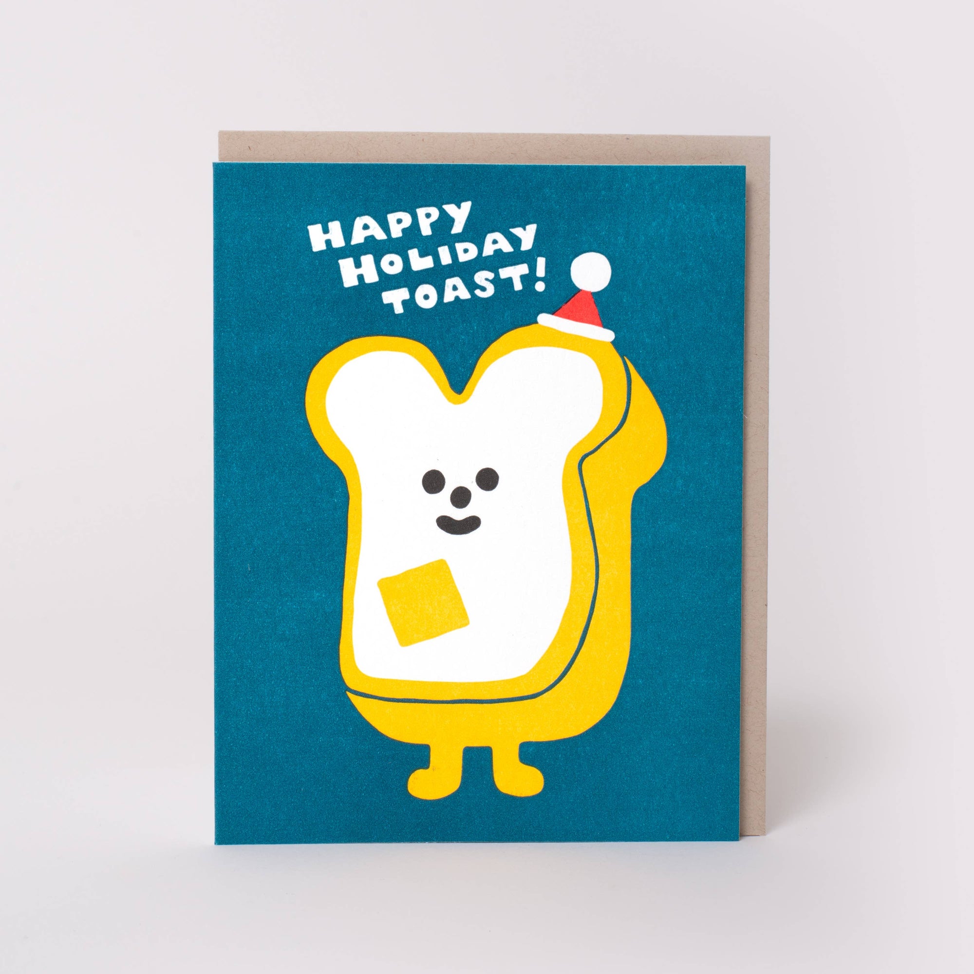 A square greeting card with a teal-blue background featuring a cartoon toast character in yellow and white, wearing a small red Santa hat. The card reads 'HAPPY HOLIDAY TOAST!' in white text.