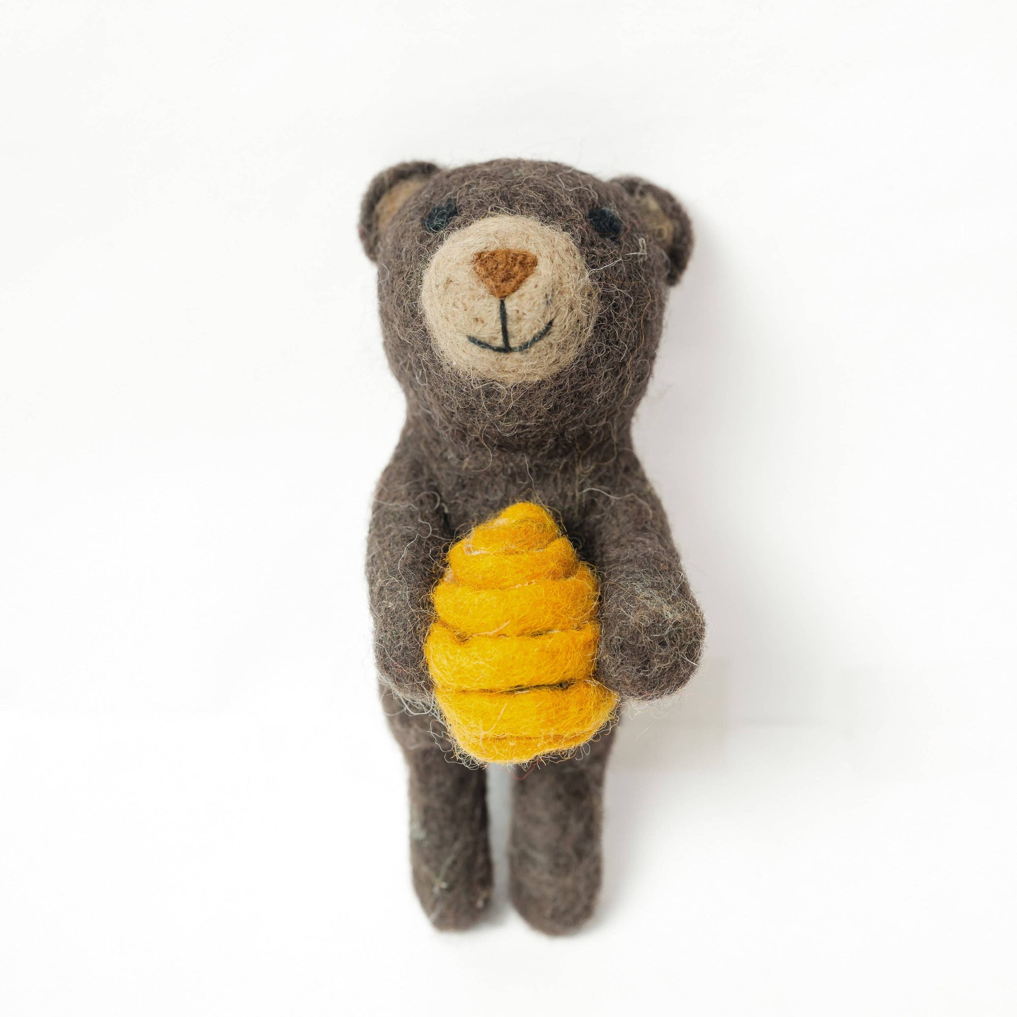 Small brown teddy bear holding a yellow honeycomb on a white background