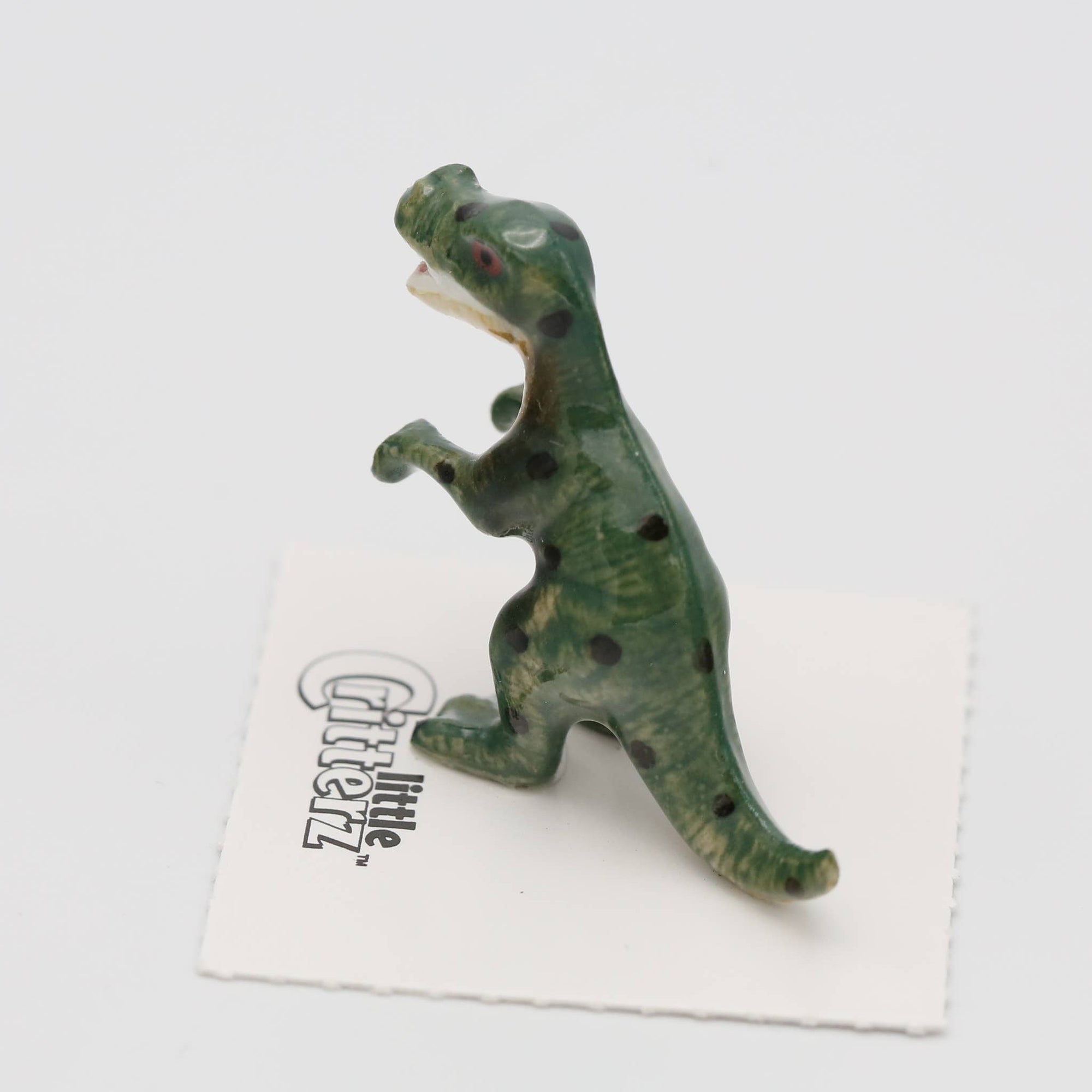 Green dinosaur figurine on a white card with text on a light gray background