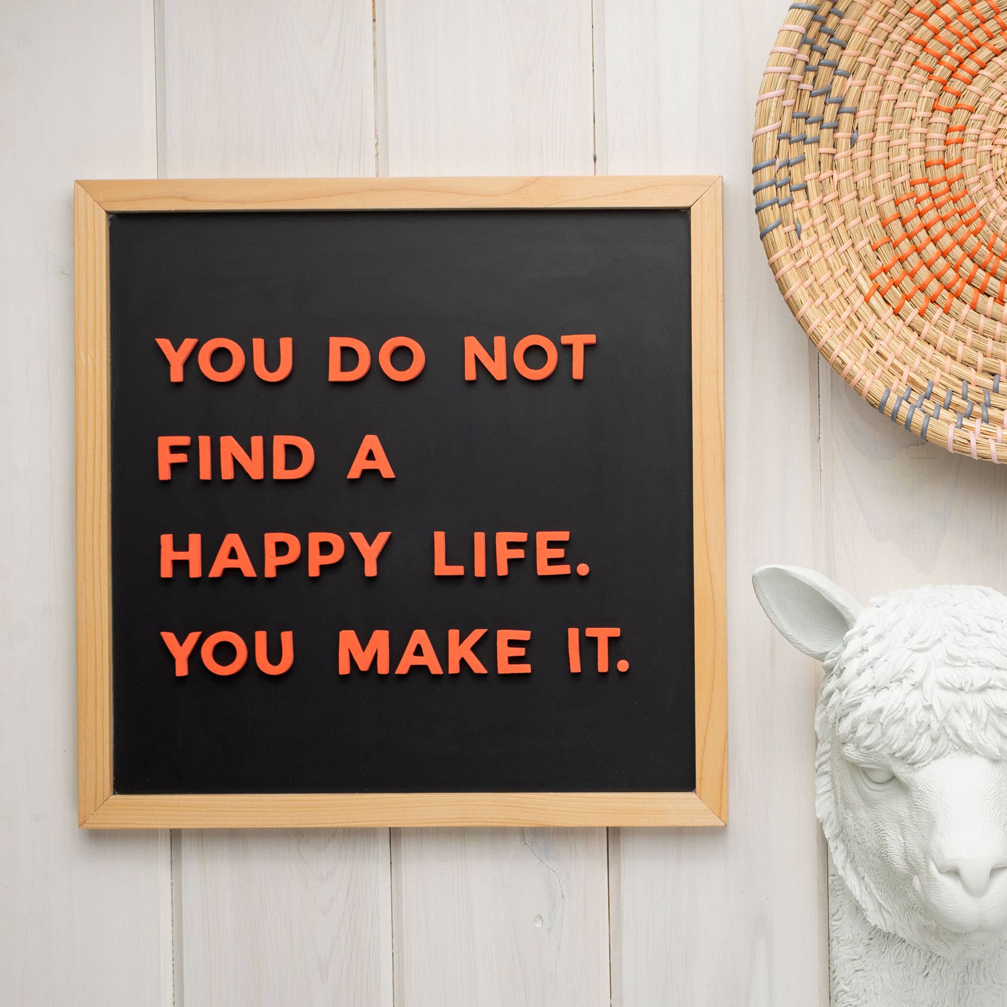 Framed quote on a black background with wooden frame, white wall and decorative items.