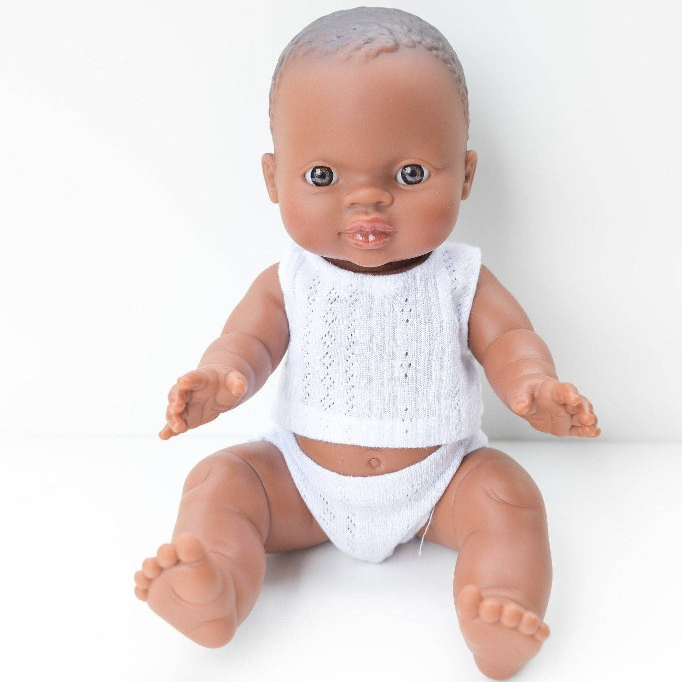 Baby doll wearing a white outfit on a white background
