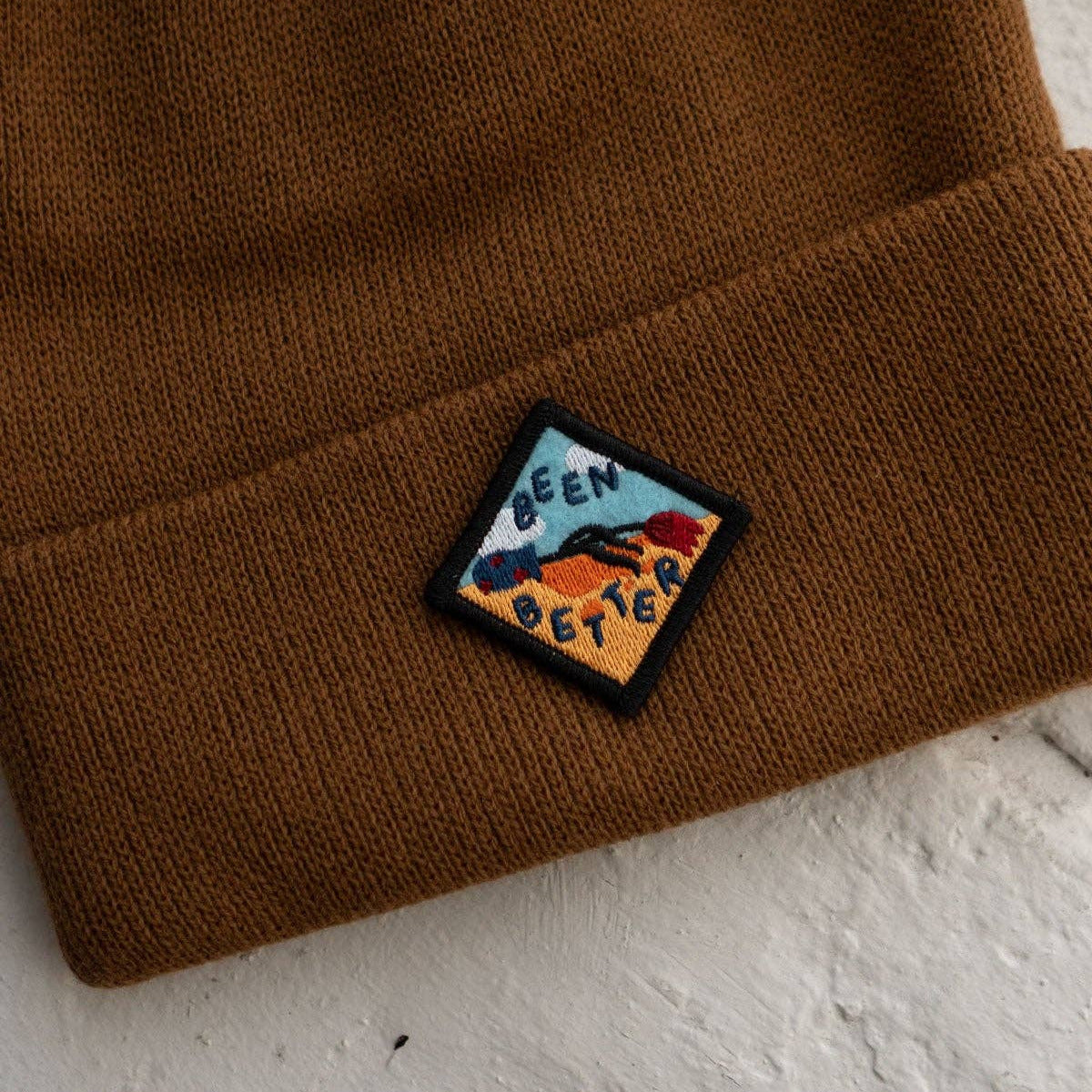 Brown beanie with a colorful patch on a white surface