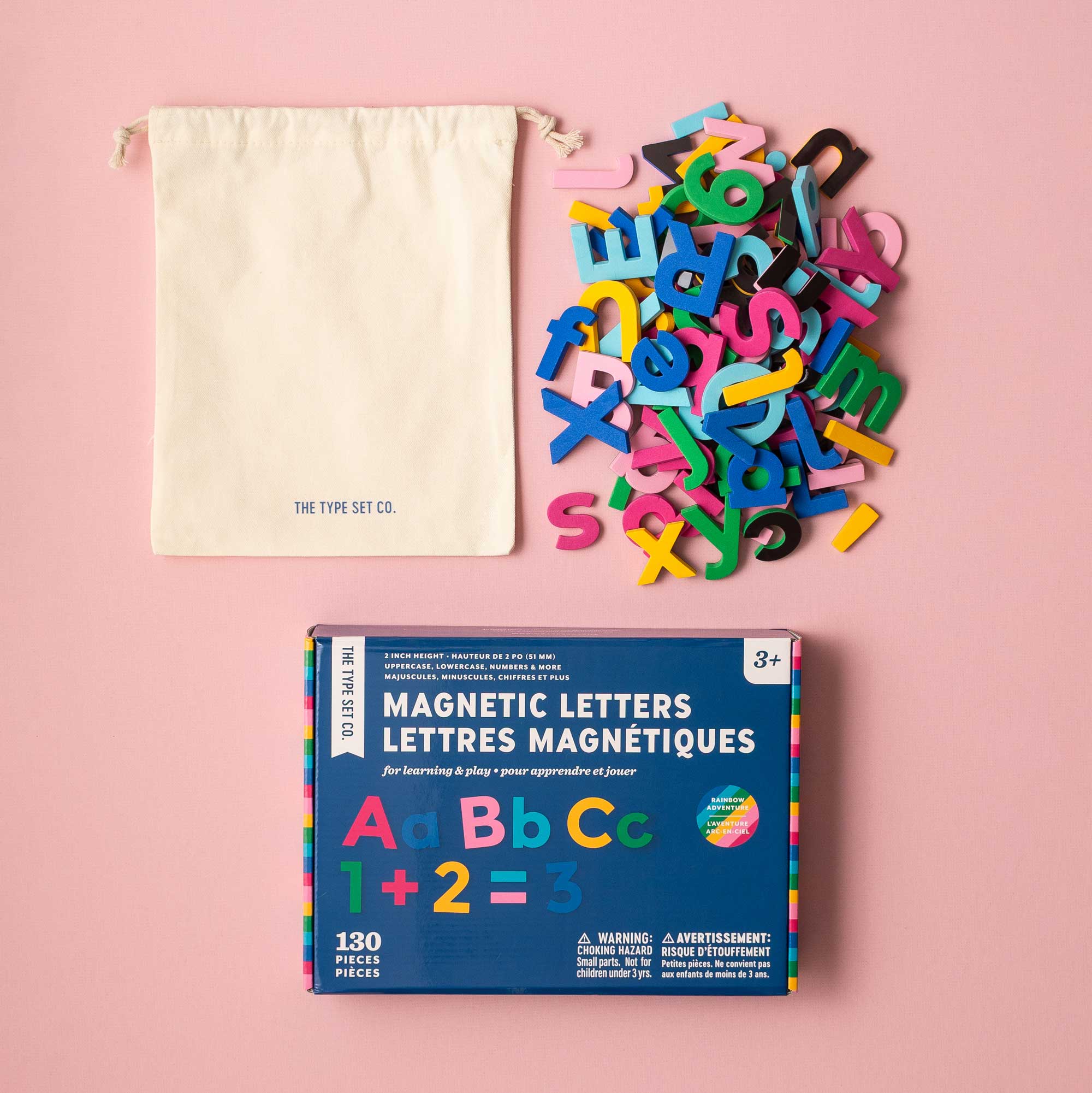 Colorful magnetic letters set with packaging and drawstring bag on a pink background