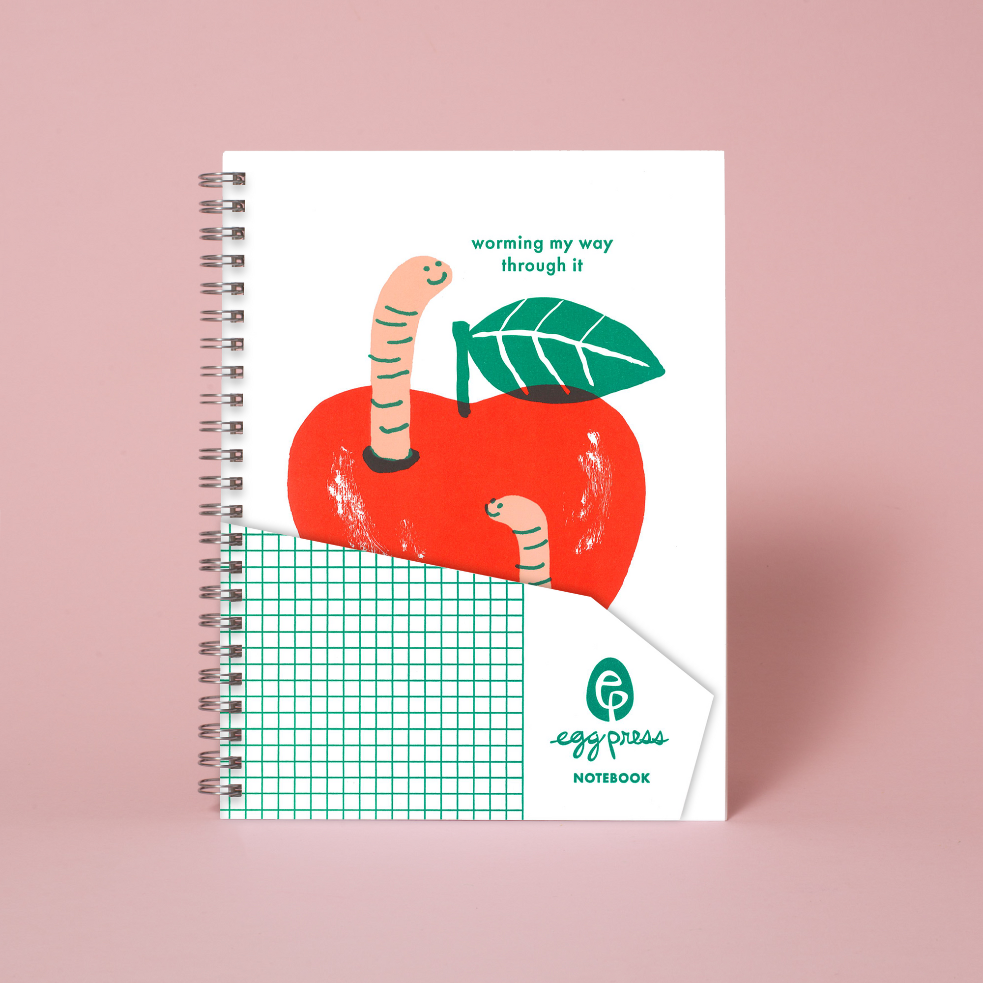 Notebook with apple and worm illustration on a pink background