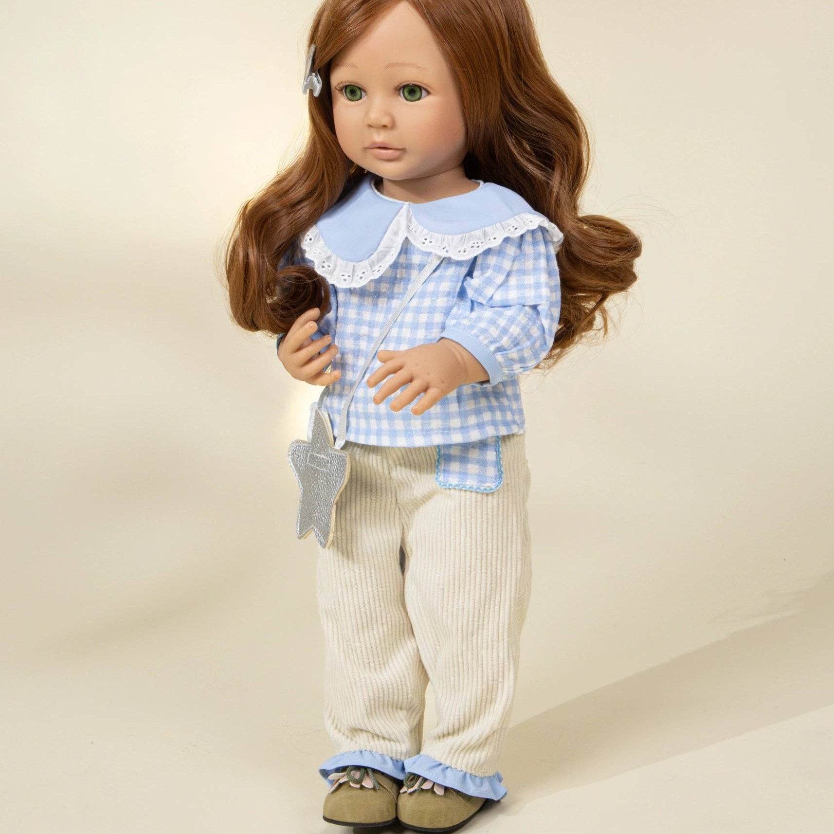 Doll wearing a blue checkered shirt and beige pants on a plain background