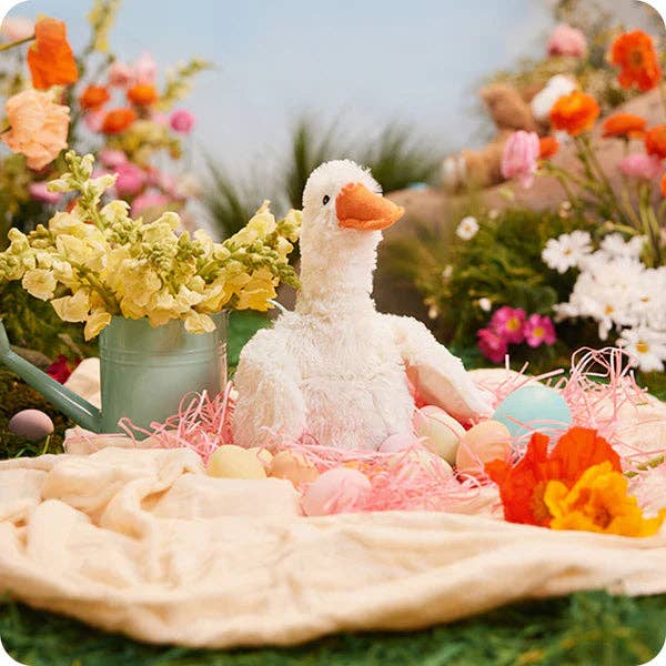 Decorative scene with a white goose, colorful eggs, and flowers on a green background