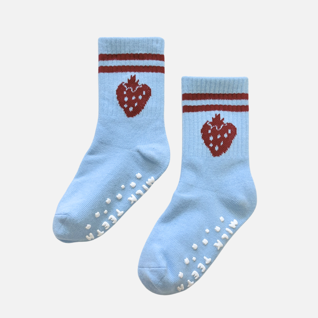 Pair of light blue socks with red strawberry design and white sole on a white background