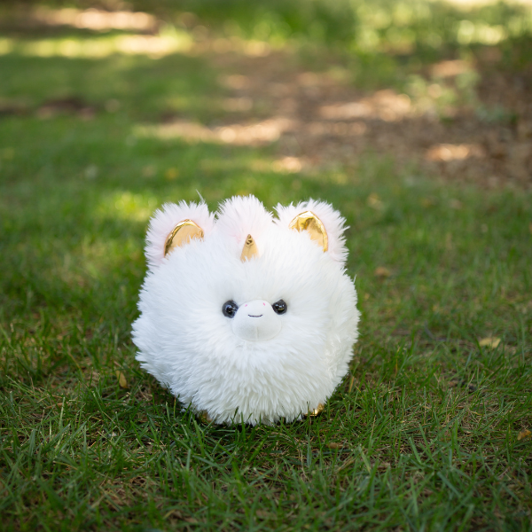 White plush toy with gold accents on grass