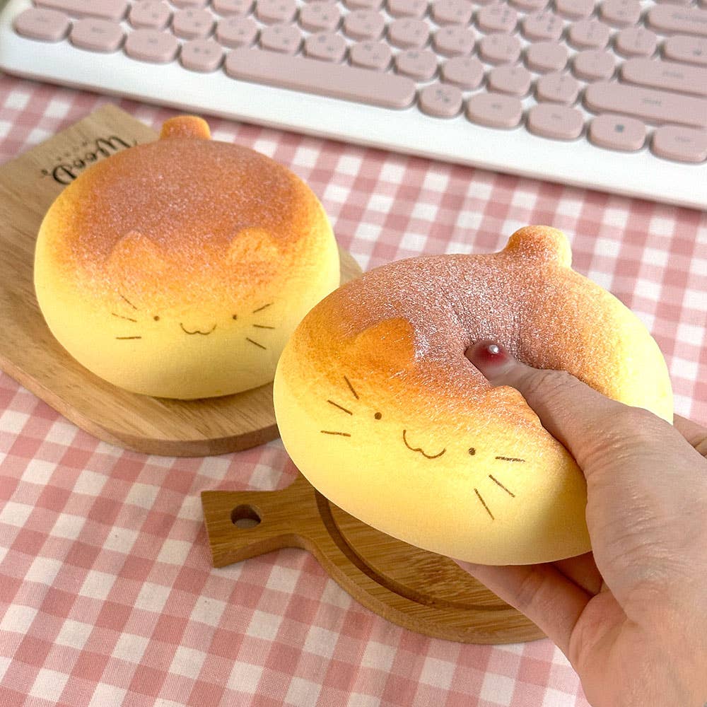 Two cat-shaped bread lights on a checkered tablecloth with a hand holding one.