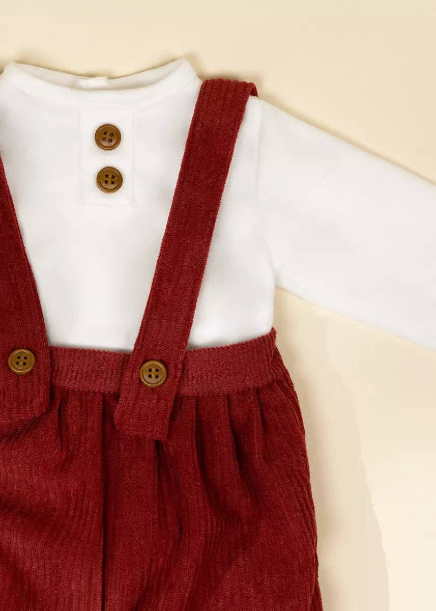 Red corduroy overalls with a white shirt on a beige background