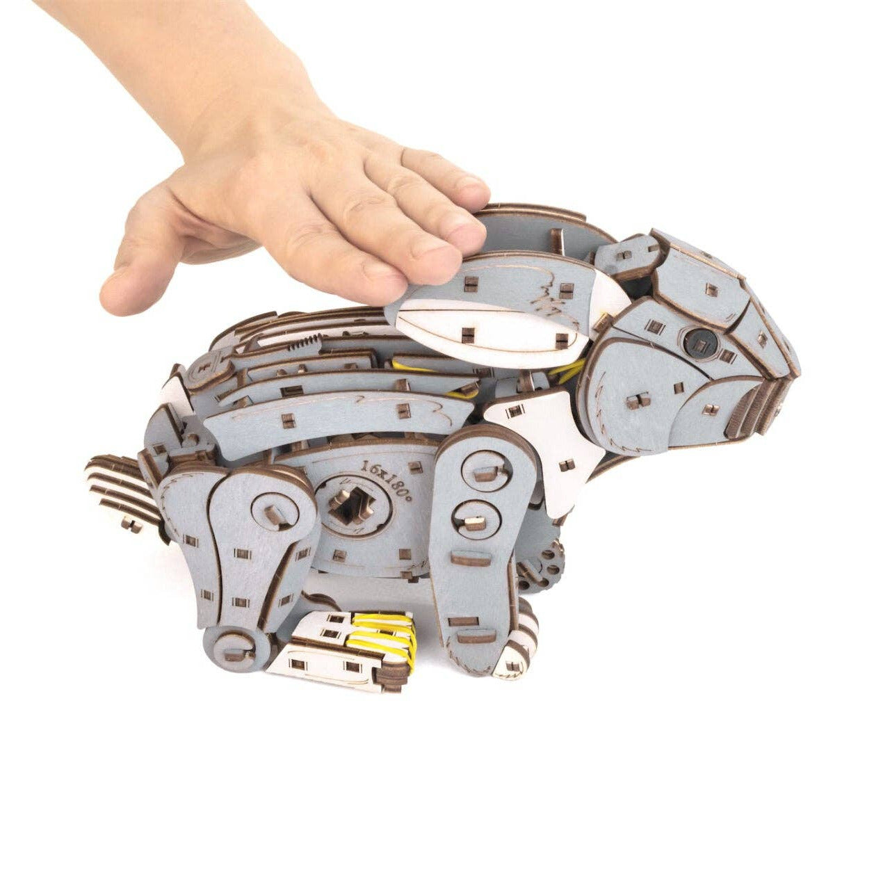 Mechanical model of a rabbit held by a hand on a white background