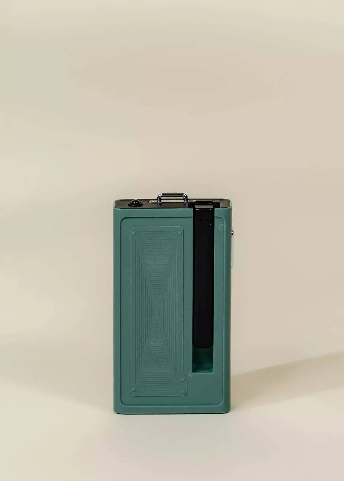 Green rectangular device with a black interior on a beige background